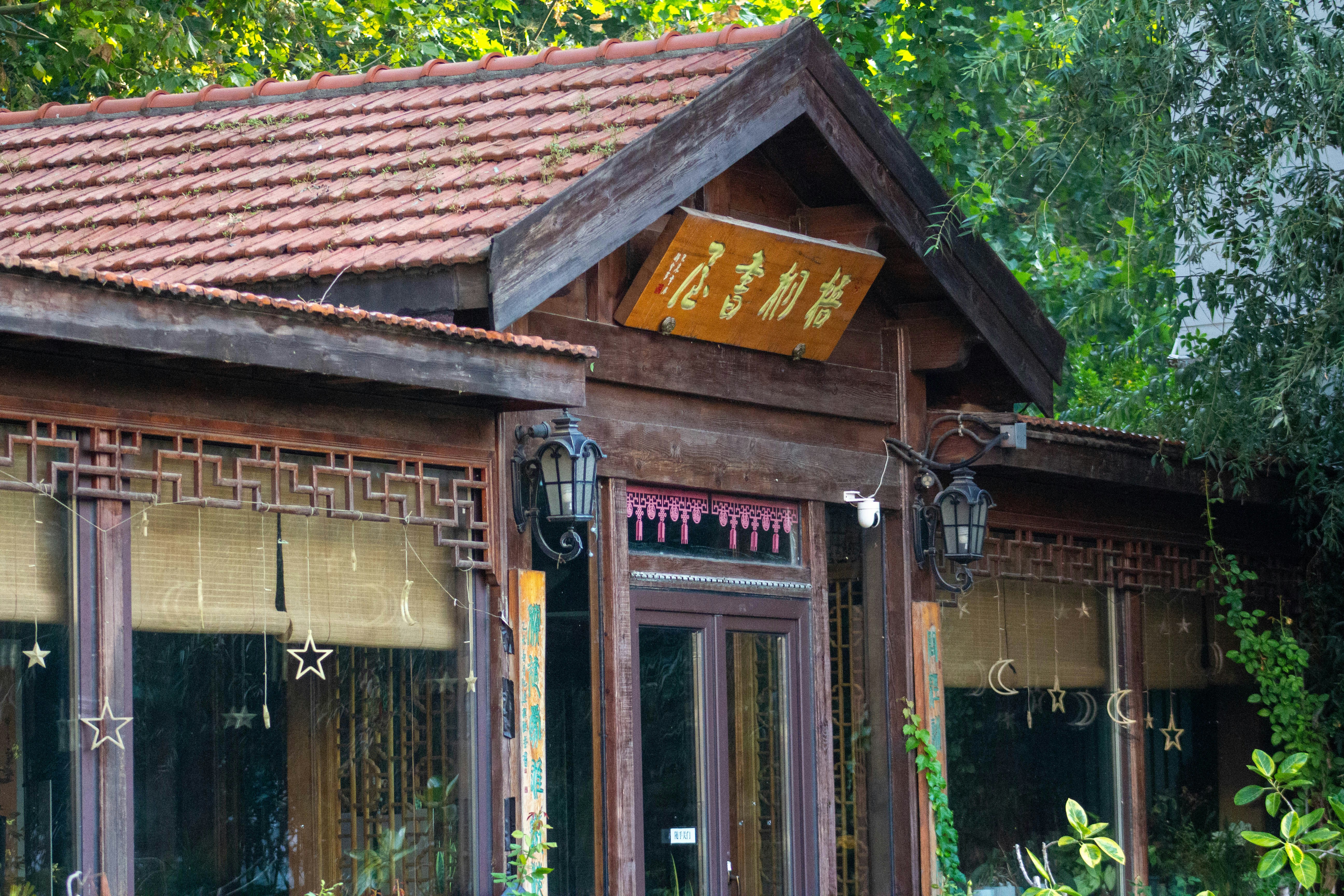 A wooden building with a tiled roof and hanging star decorations in a garden