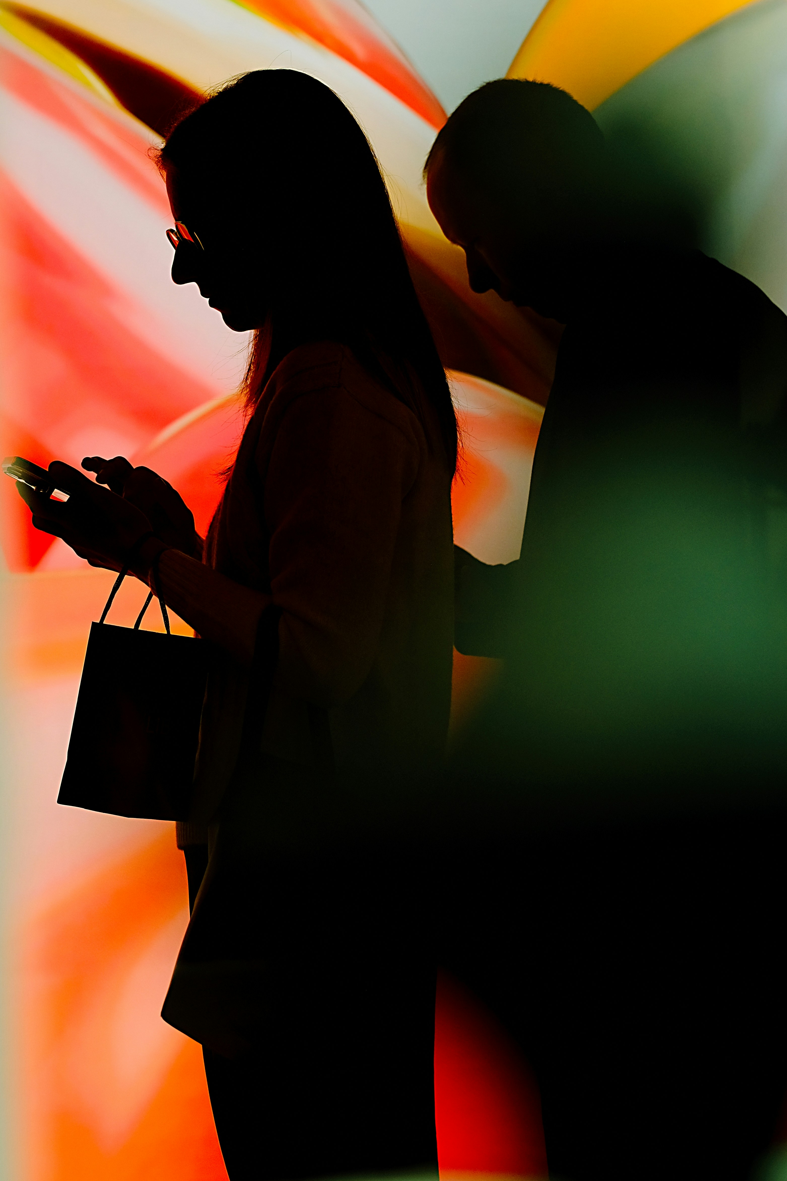 Silhouettes of two people against a vibrant orange and green light display