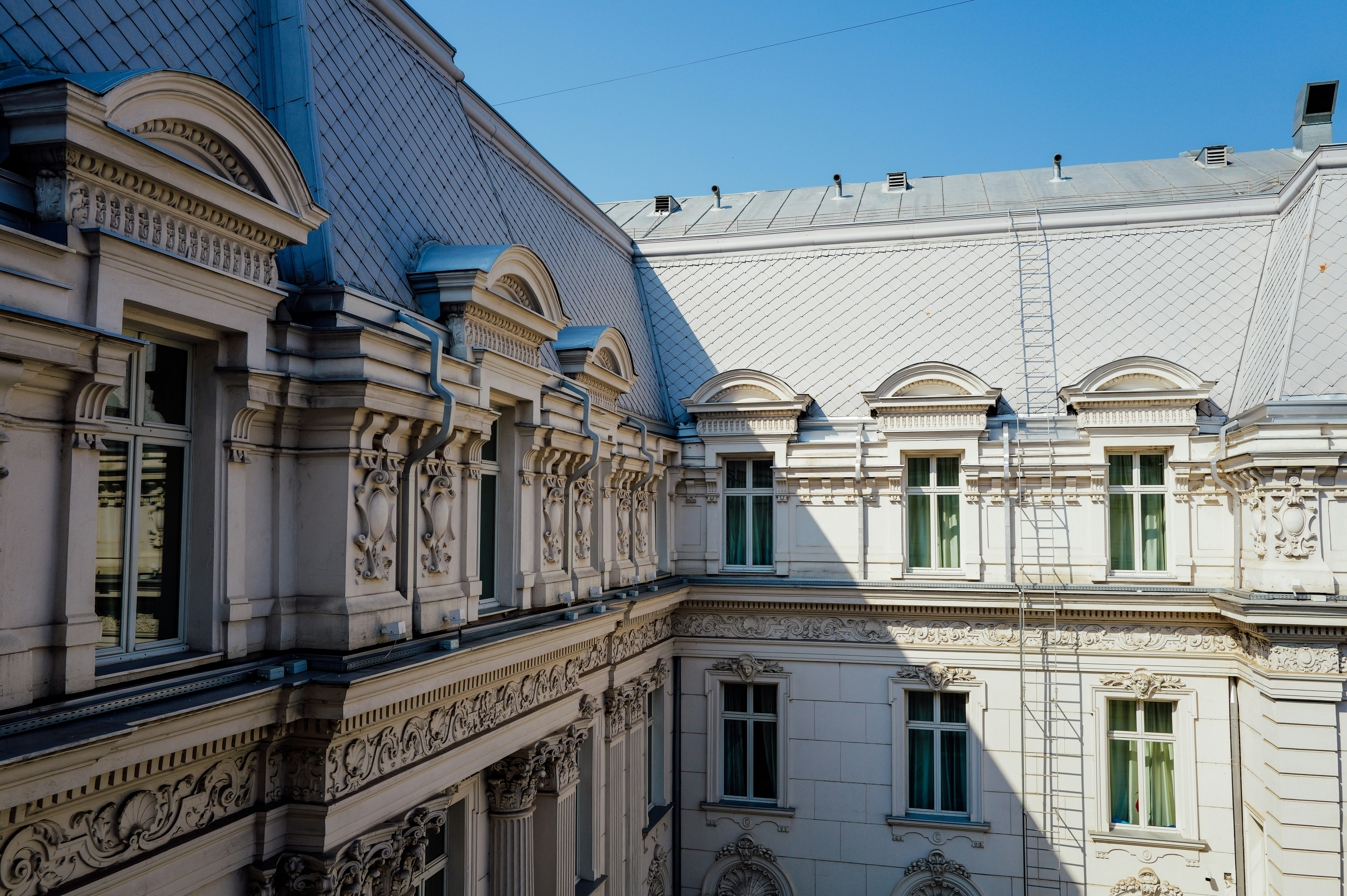 Ornate white neoclassical building facade with arched windows and a grey tiled roof