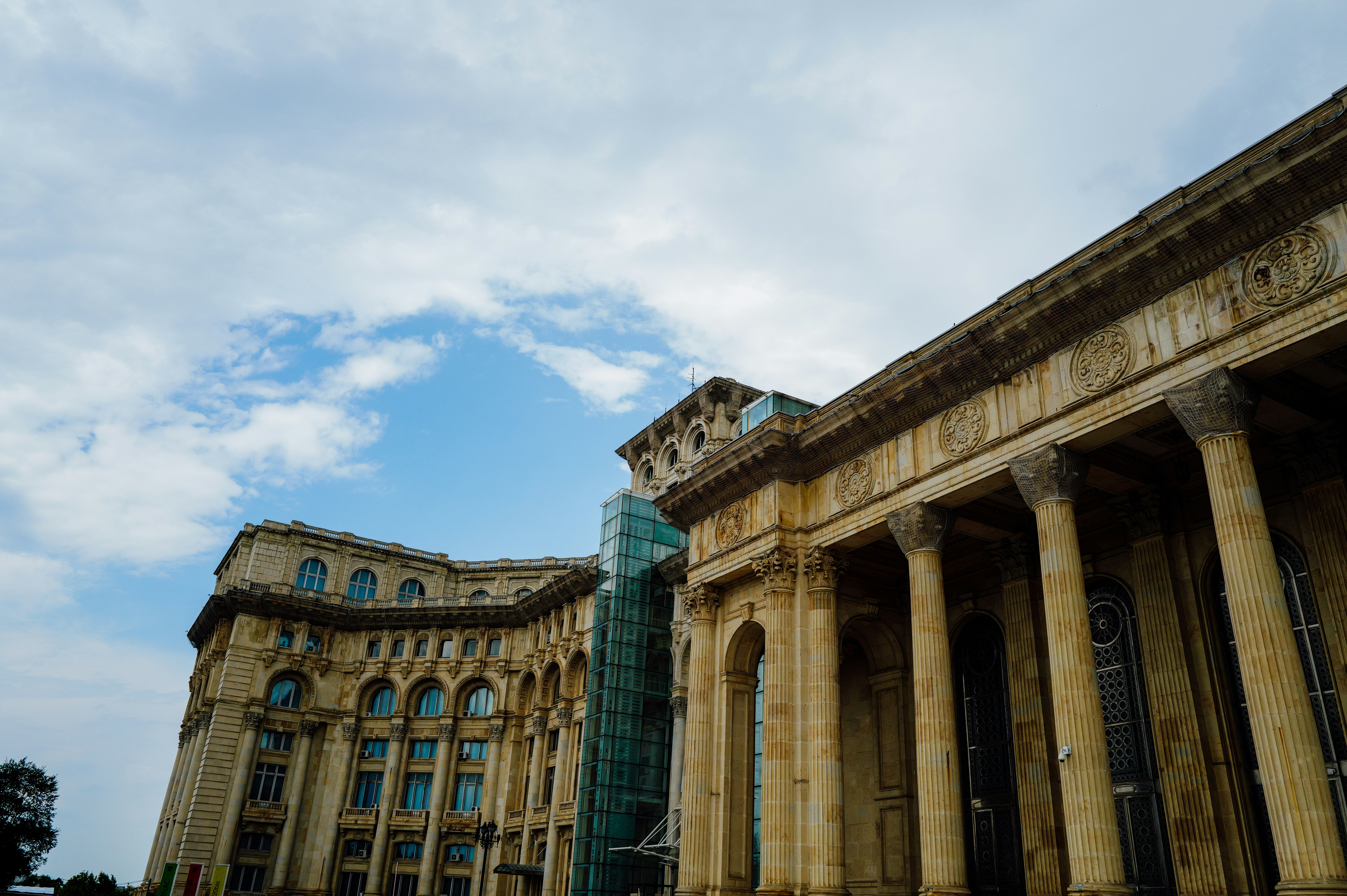 Neoclassical building facade with tall columns and arched windows under a cloudy sky