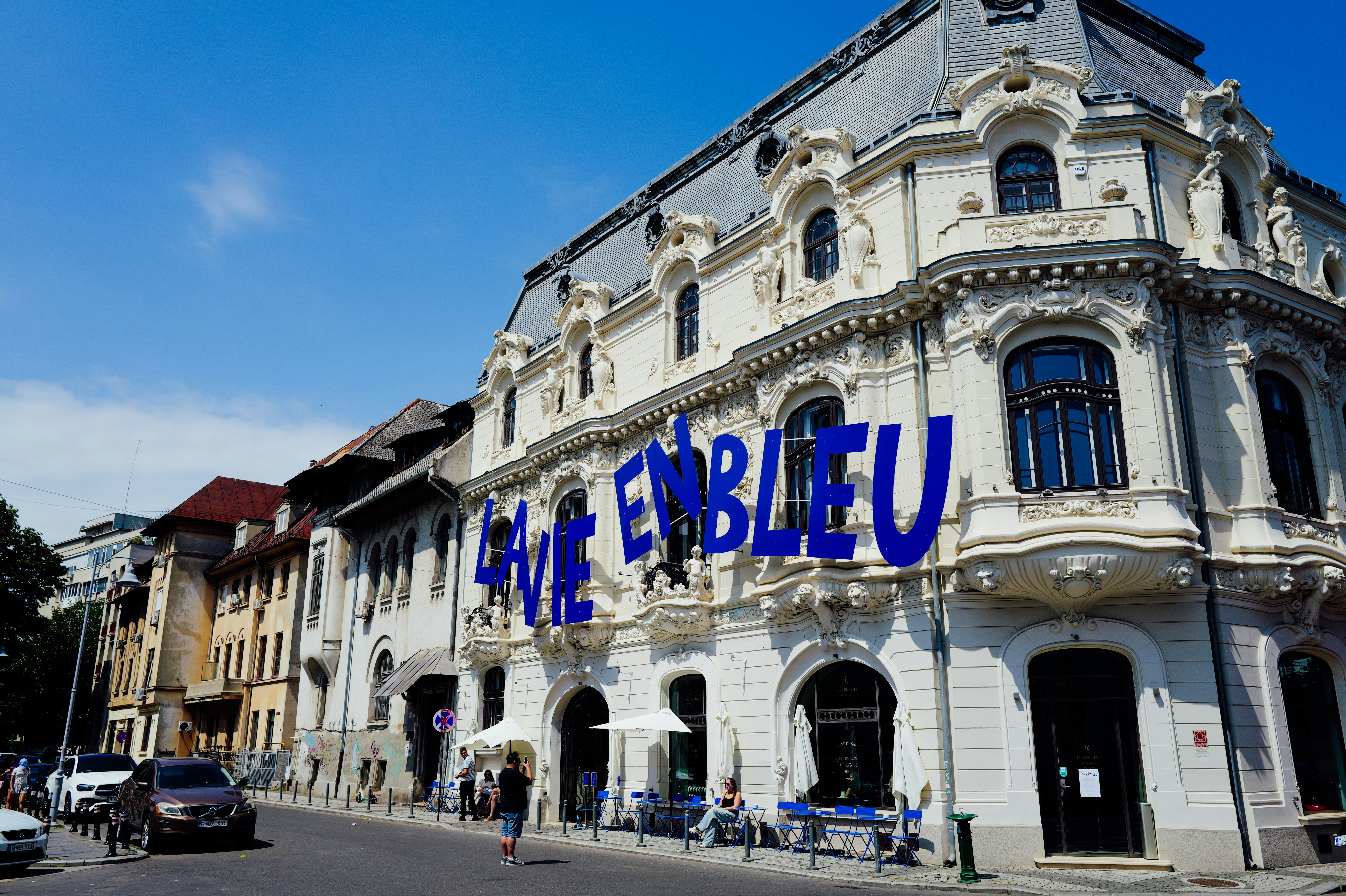 A historic building with blue lettering reading "LA VIE EN BLEU" on a street