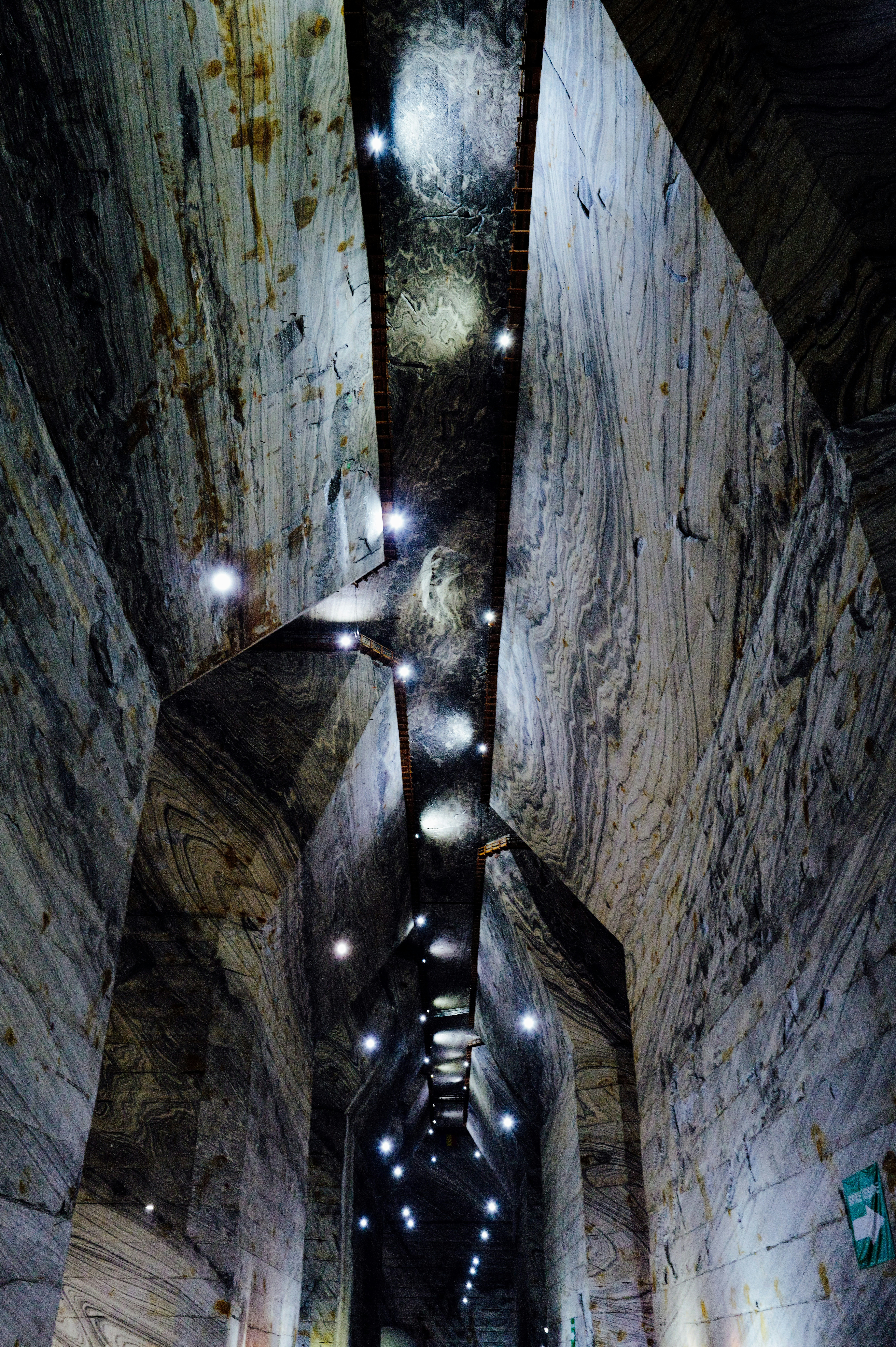 A deep underground salt mine chamber with towering walls of layered grey rock