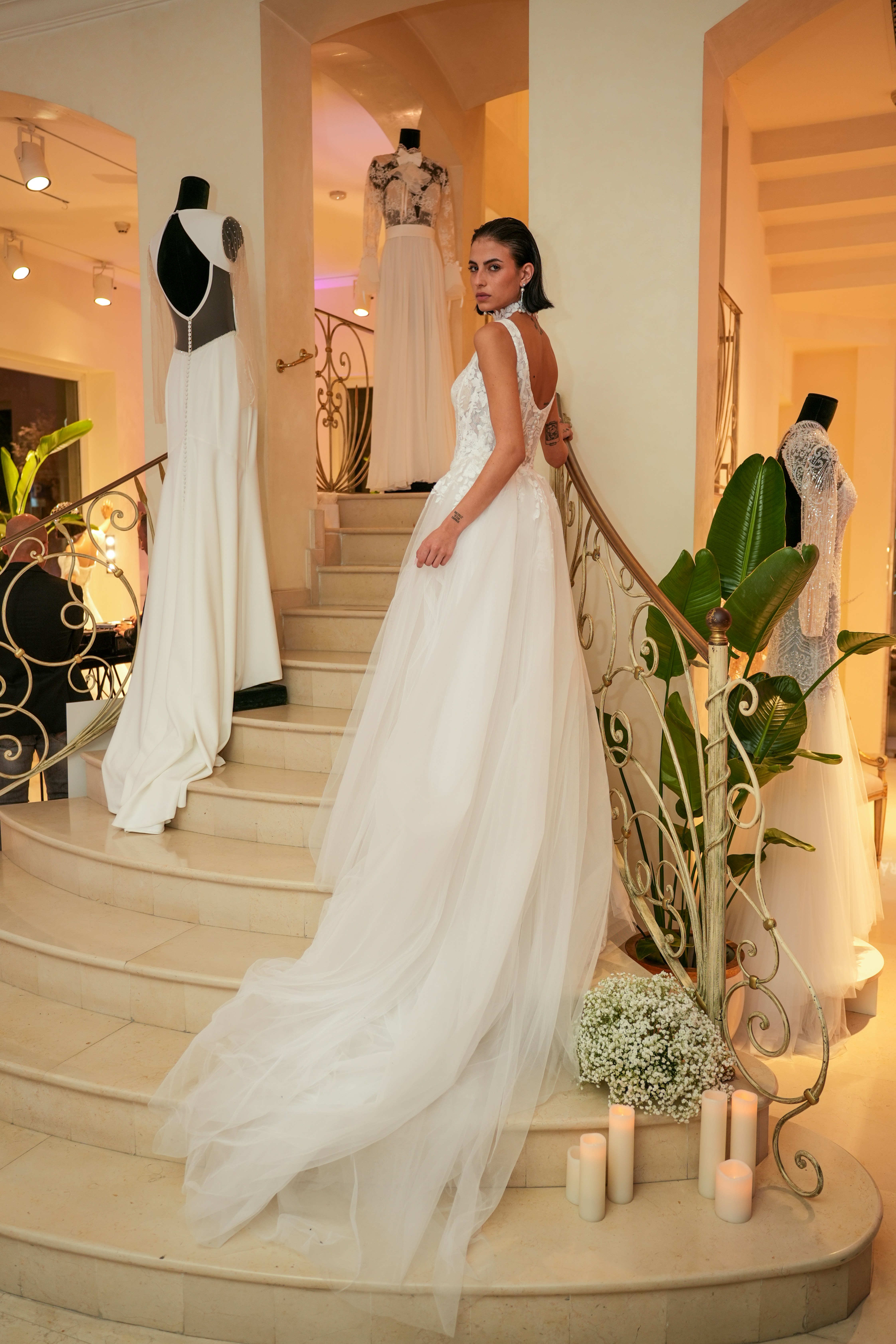 A woman in a white lace wedding dress on a staircase in a boutique