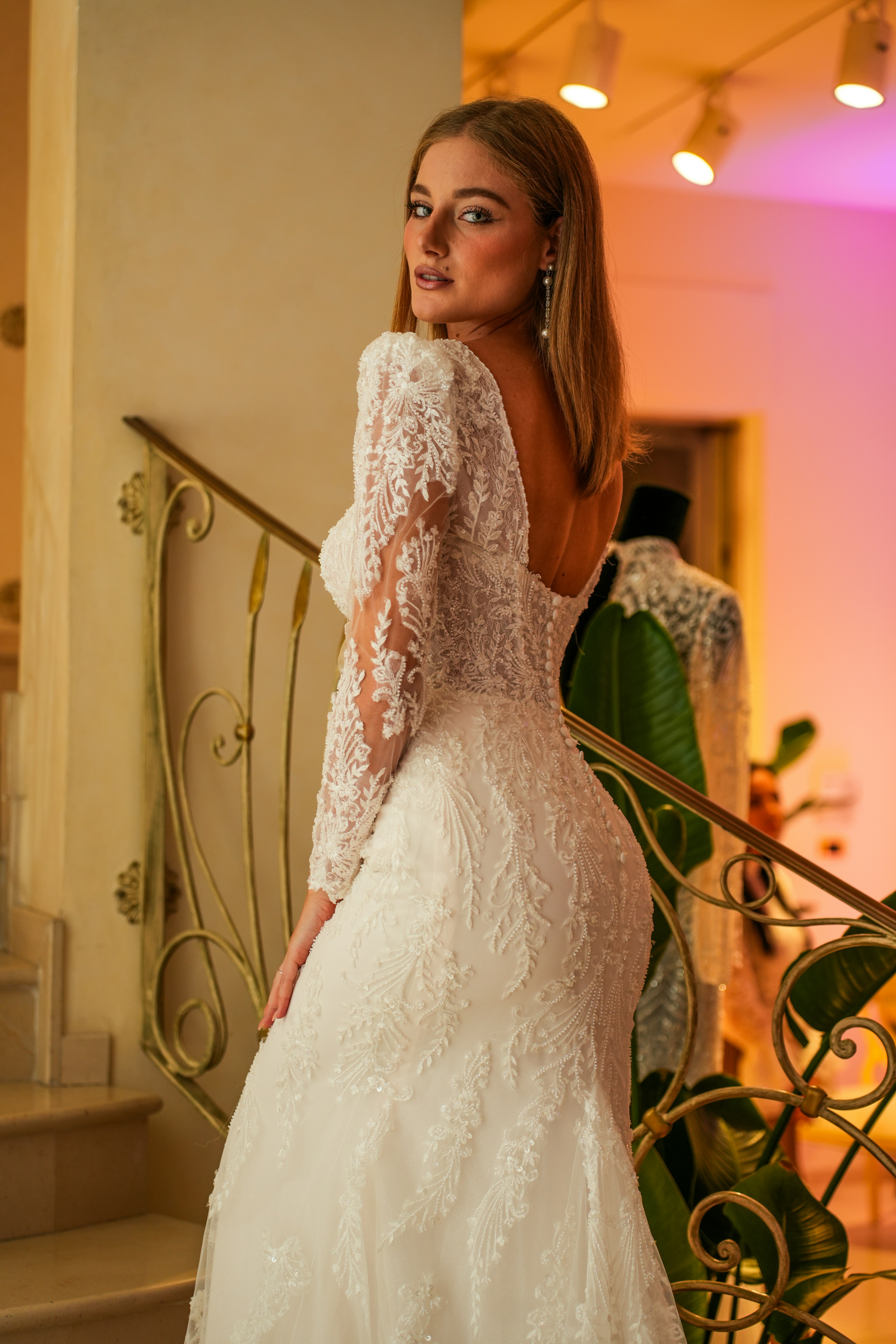 A woman in a white lace wedding dress standing on a staircase
