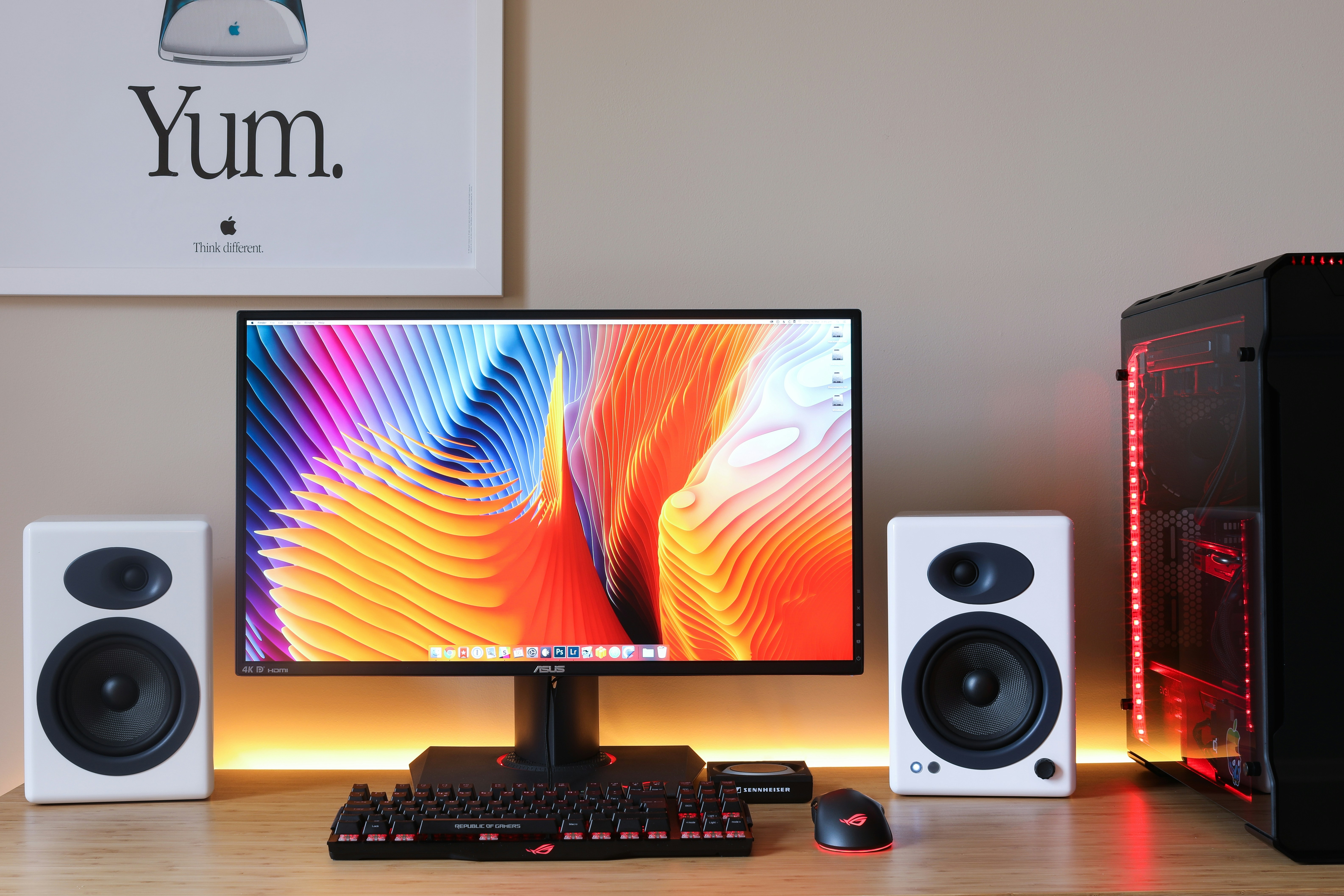 A computer monitor with colorful abstract wallpaper, speakers, and a gaming keyboard on a desk