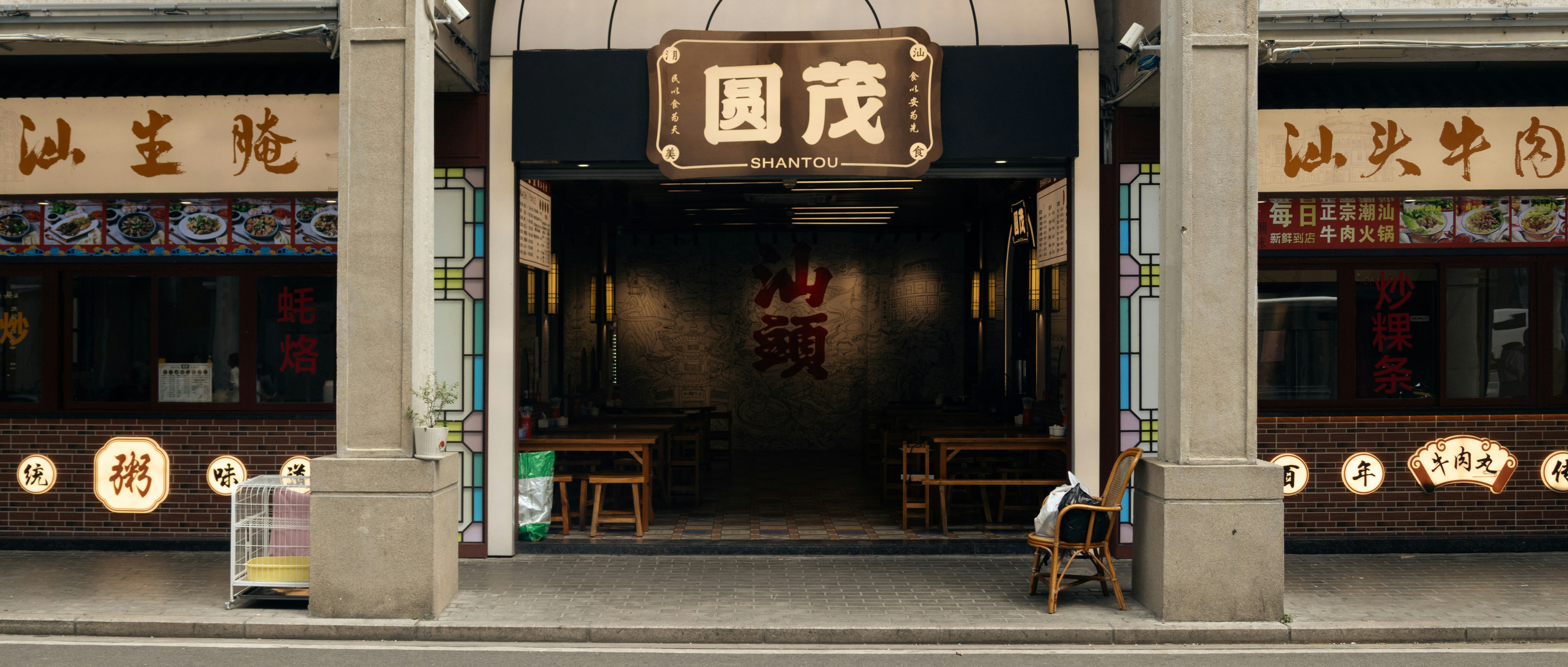 A restaurant storefront with Chinese signage and wooden tables in Shantou