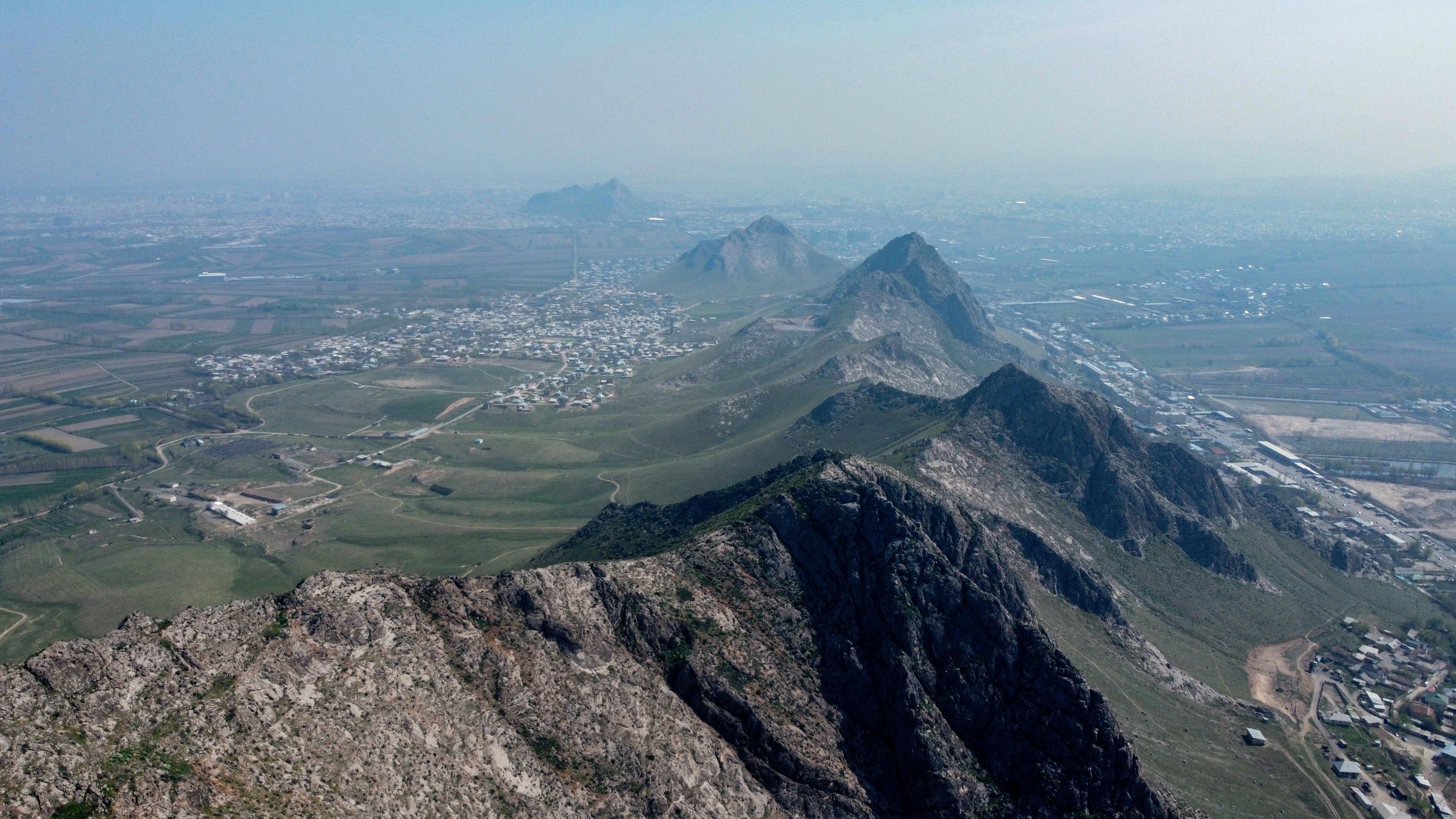 Aerial view of a rocky mountain ridge overlooking a valley with small towns