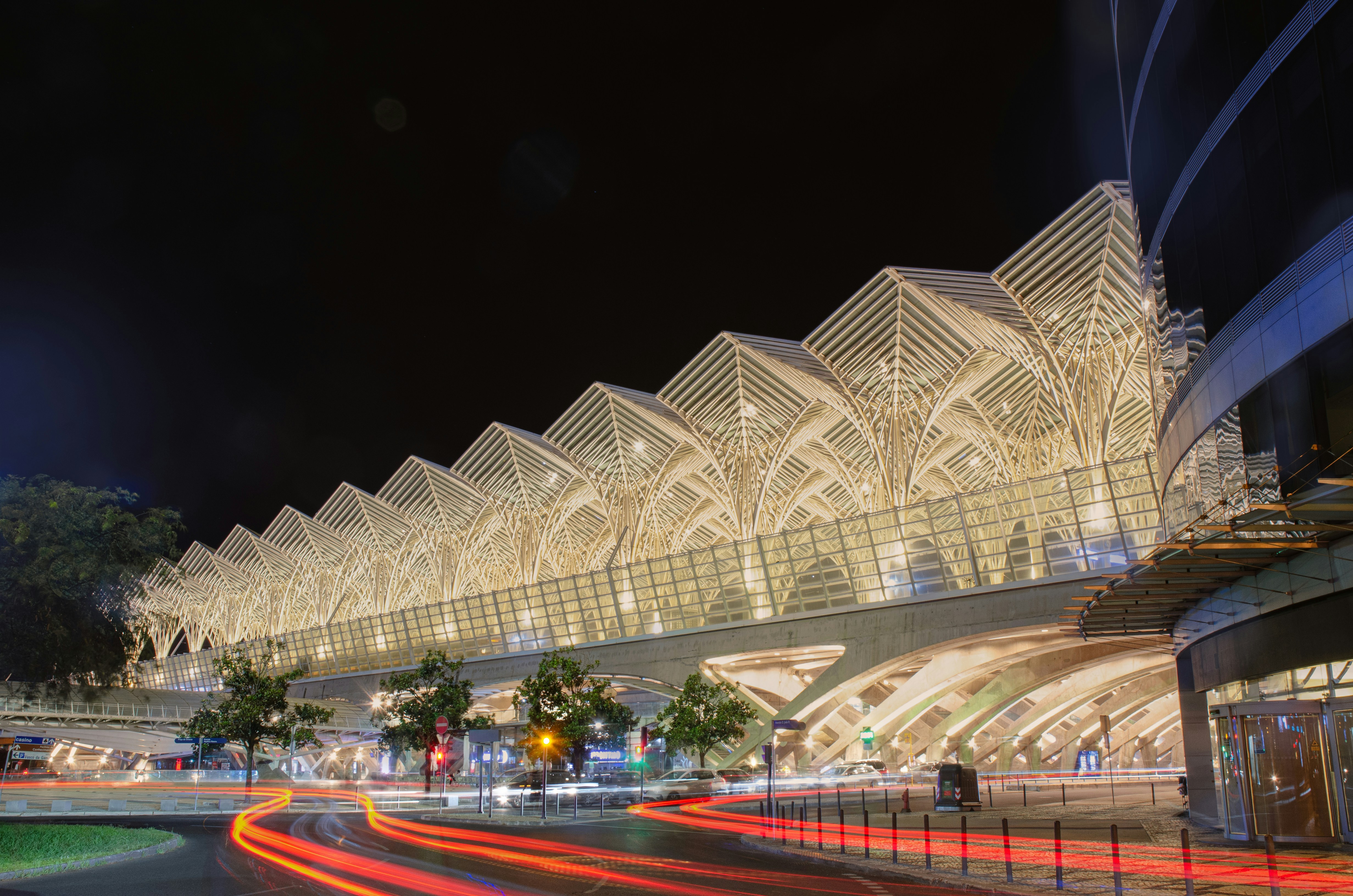 Long exposure light trails on a road beneath the illuminated Gare do Oriente in Lisbon