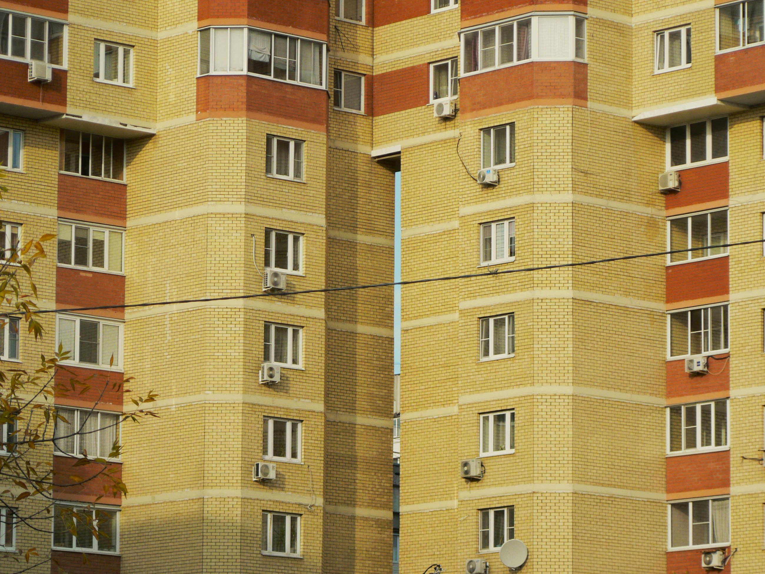 Yellow brick apartment buildings with many windows and air conditioning units