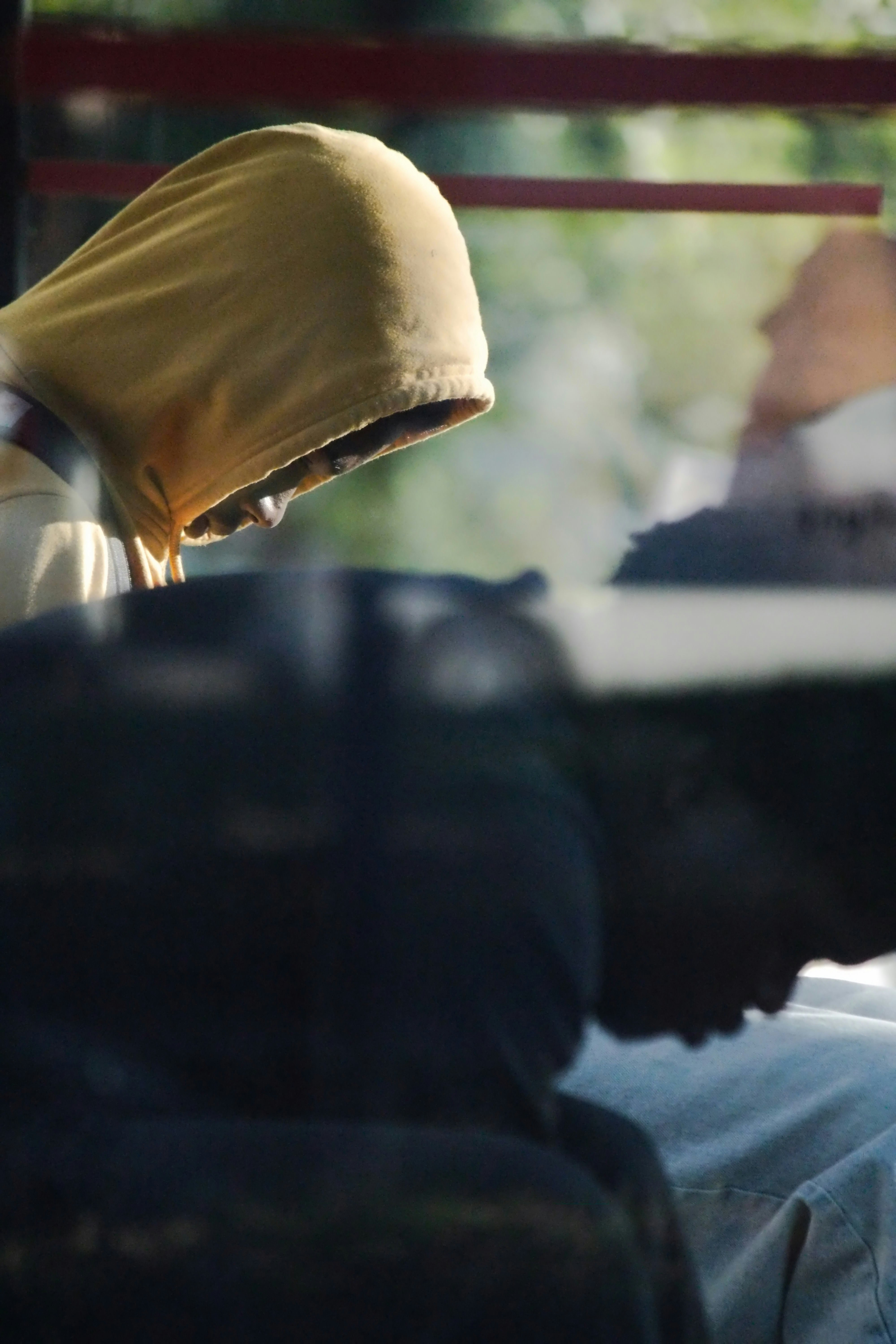 A person in a yellow hooded sweatshirt looking down in a dimly lit space