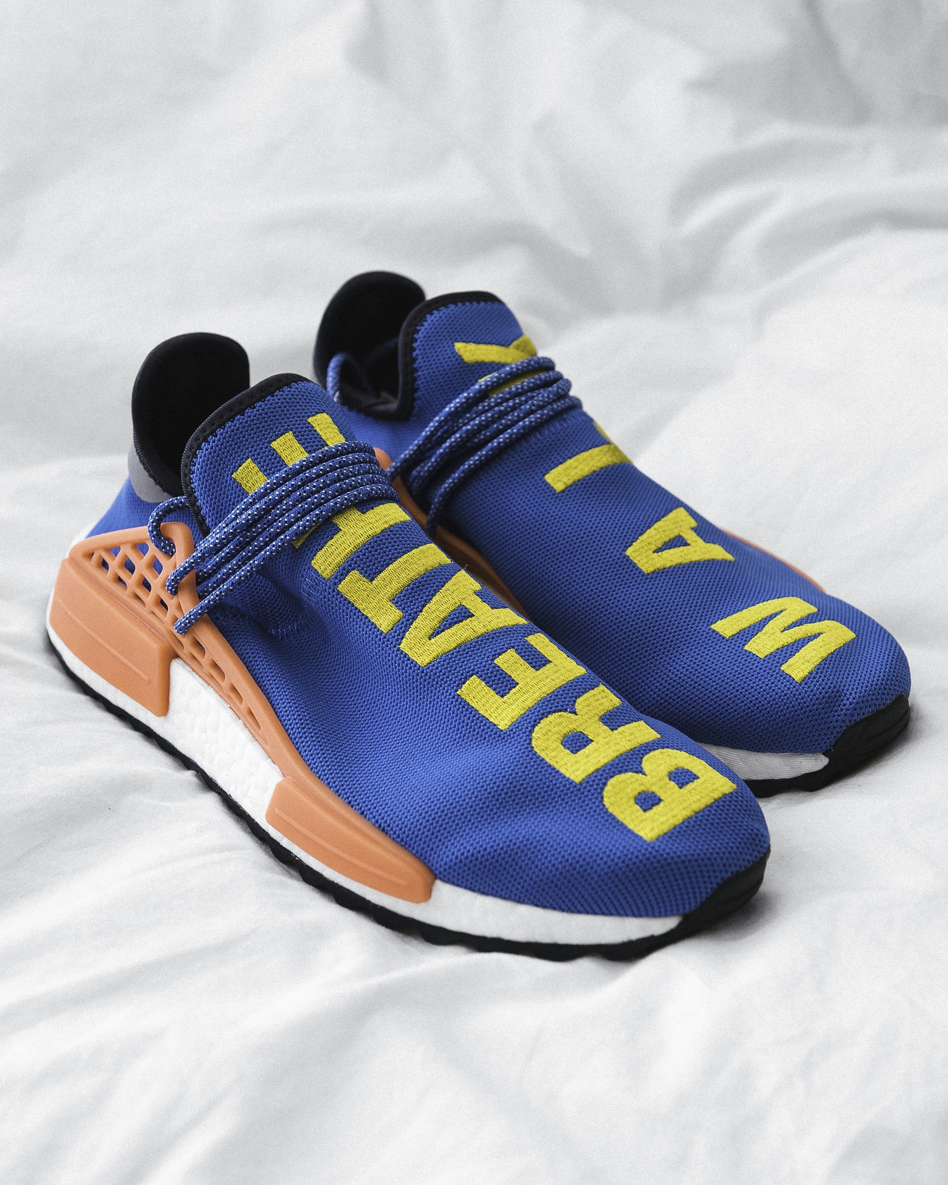 Blue sneakers with yellow text on a white fabric surface