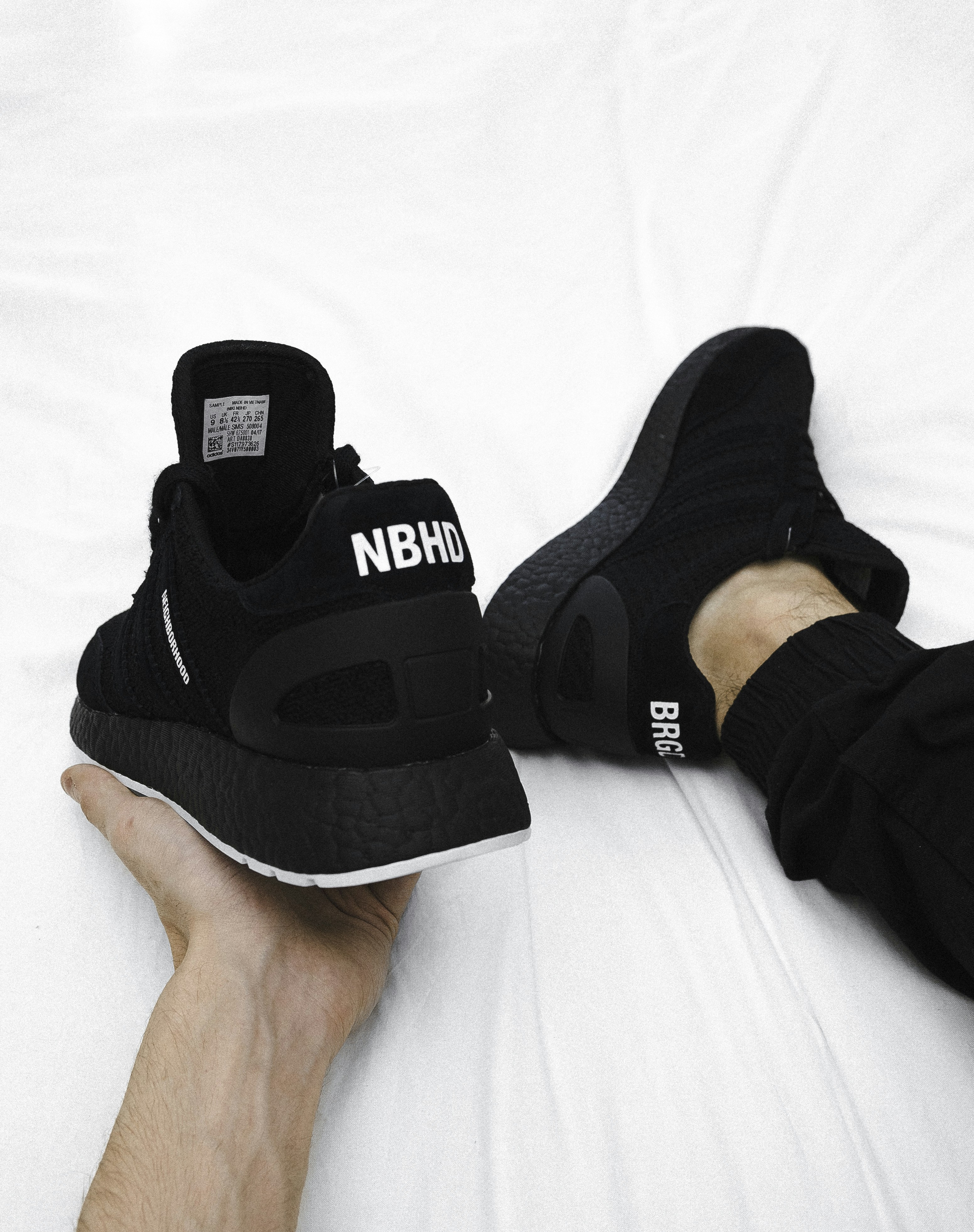 A person holding a black sneaker with white text on a white background