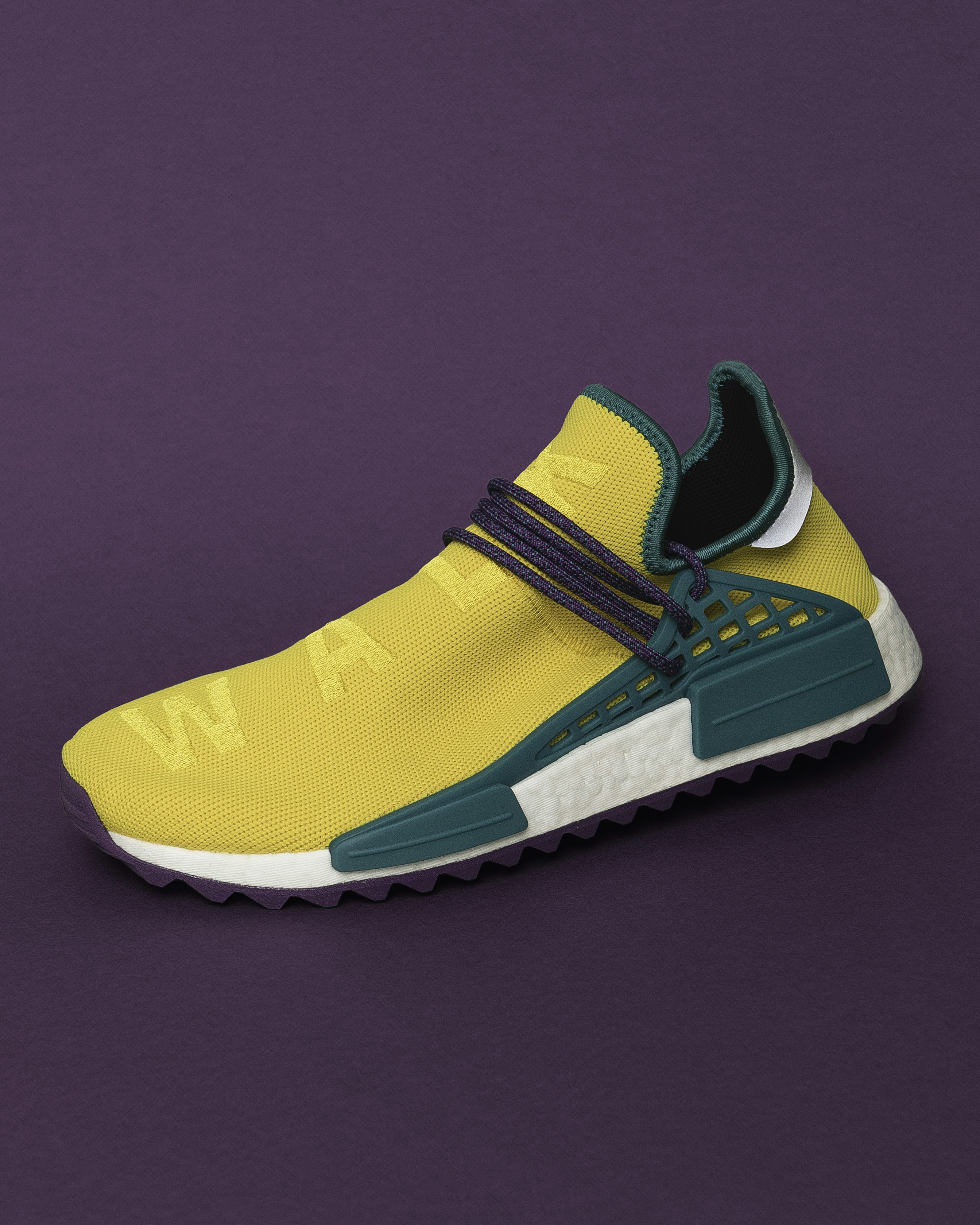 A yellow sneaker with teal accents and purple laces on a purple background