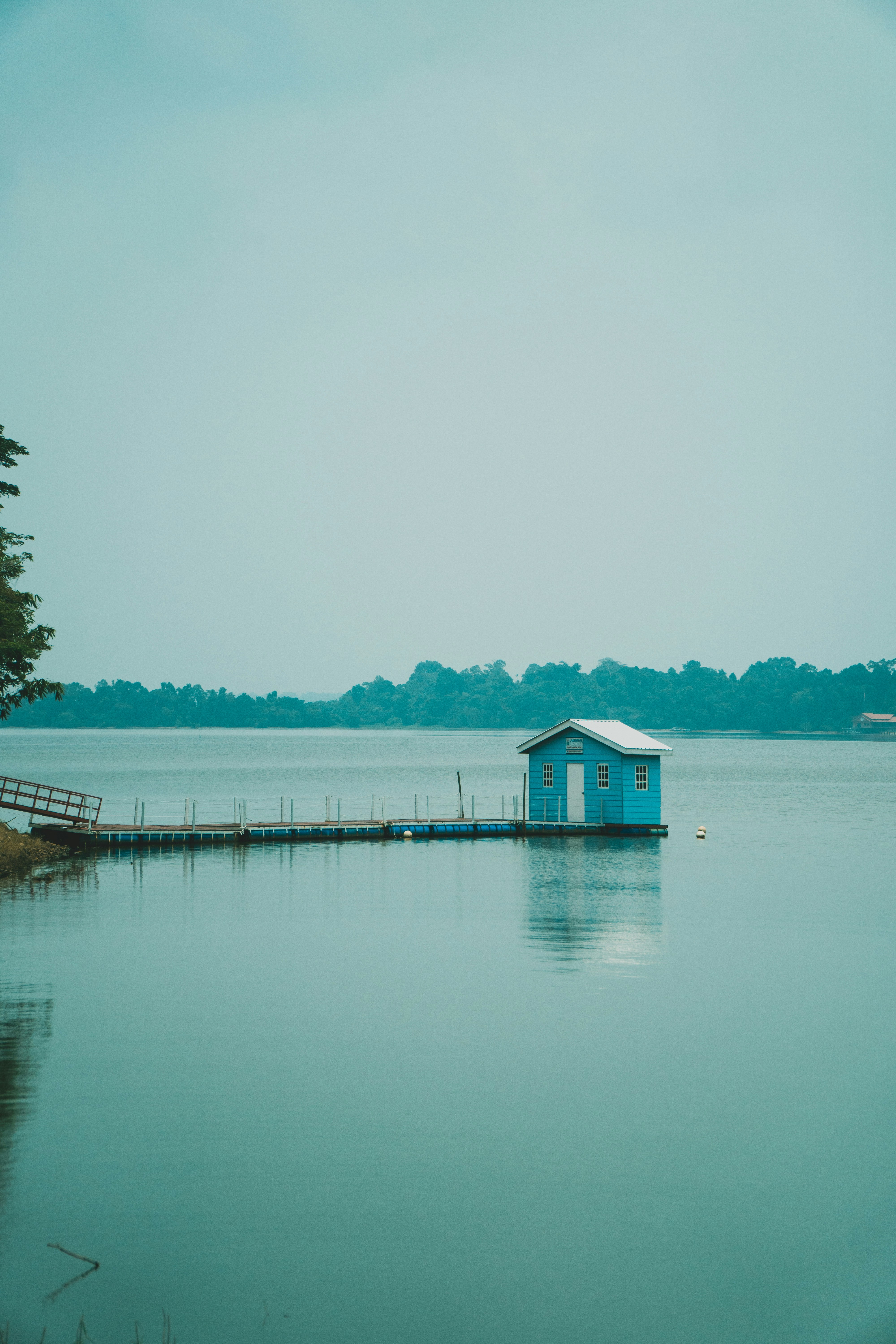 A small blue cabin on a floating dock in a calm lake