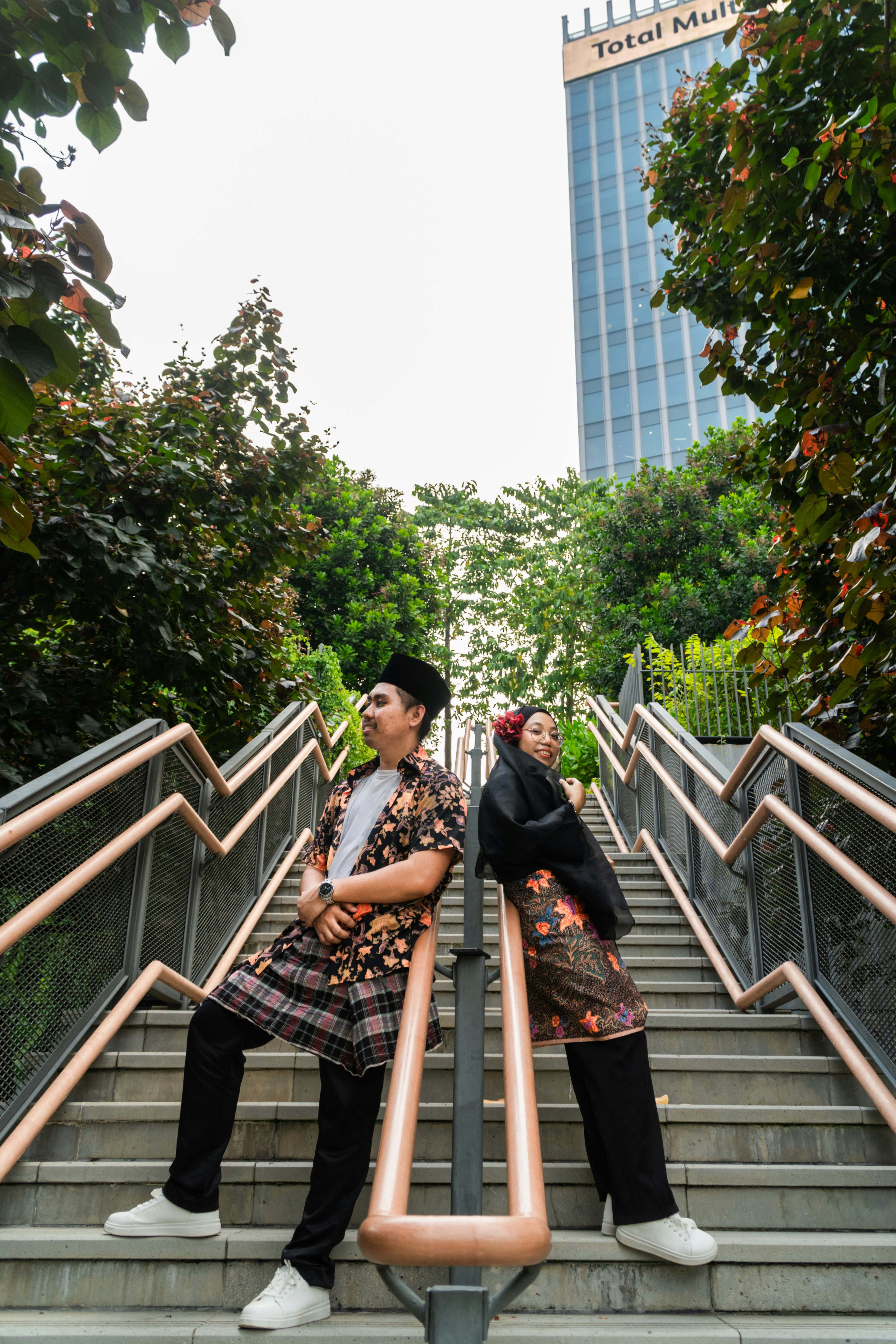 A man and a woman in traditional attire standing back to back on outdoor stairs
