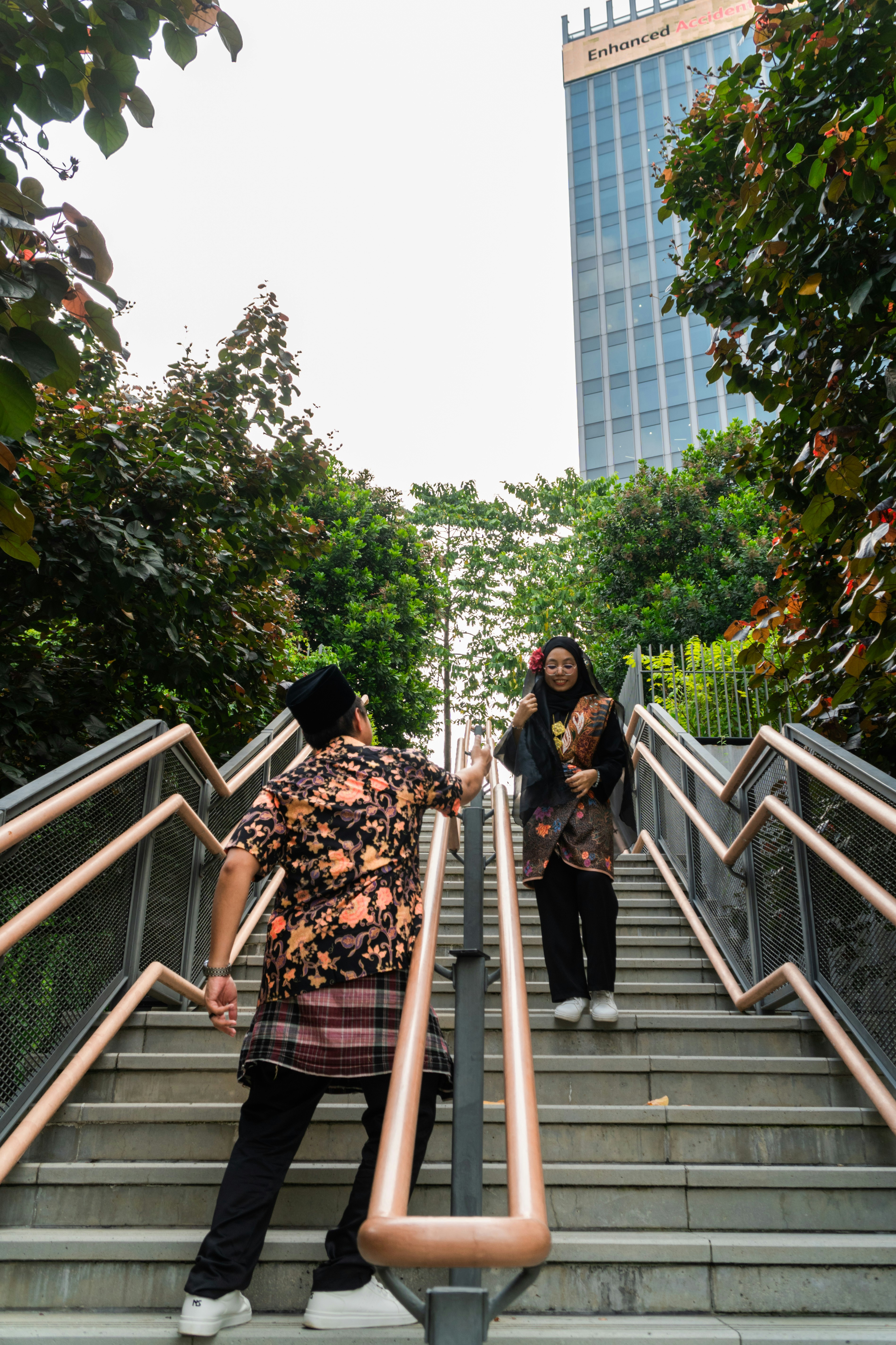 A man and a woman in traditional batik clothing on outdoor stairs