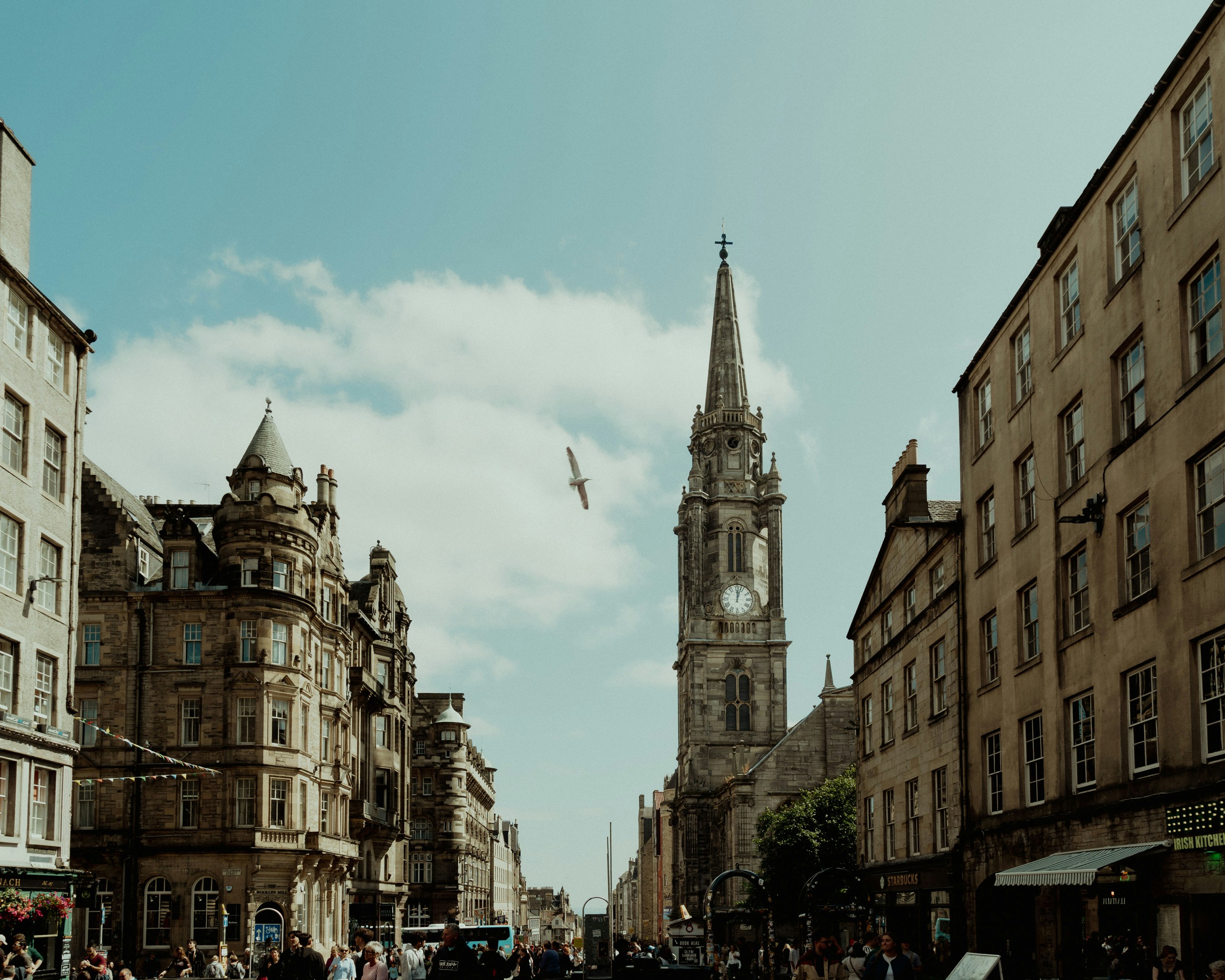 A stone church spire rising above historic buildings on a street in Edinburgh