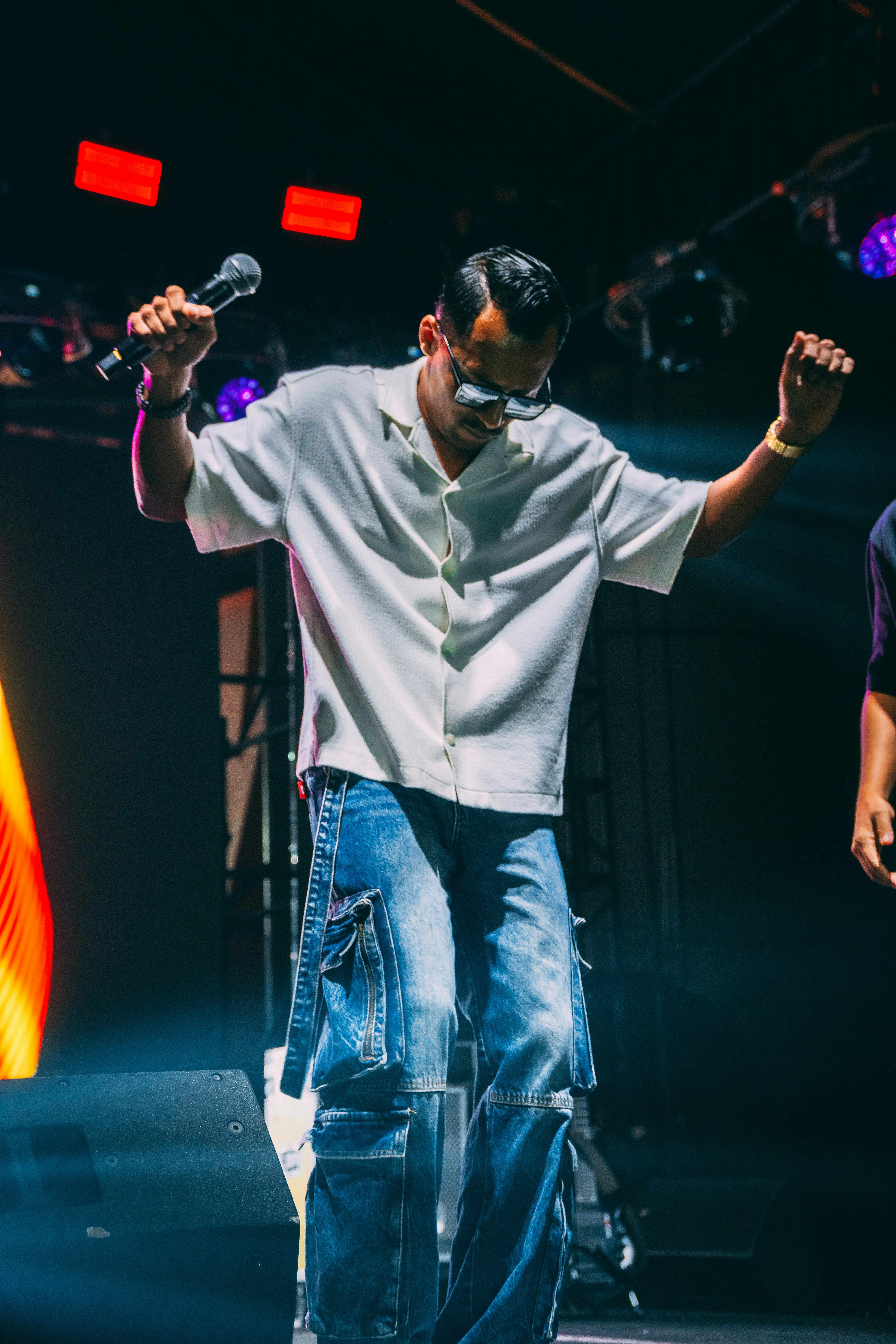 A man in a white shirt and blue cargo jeans performing on stage