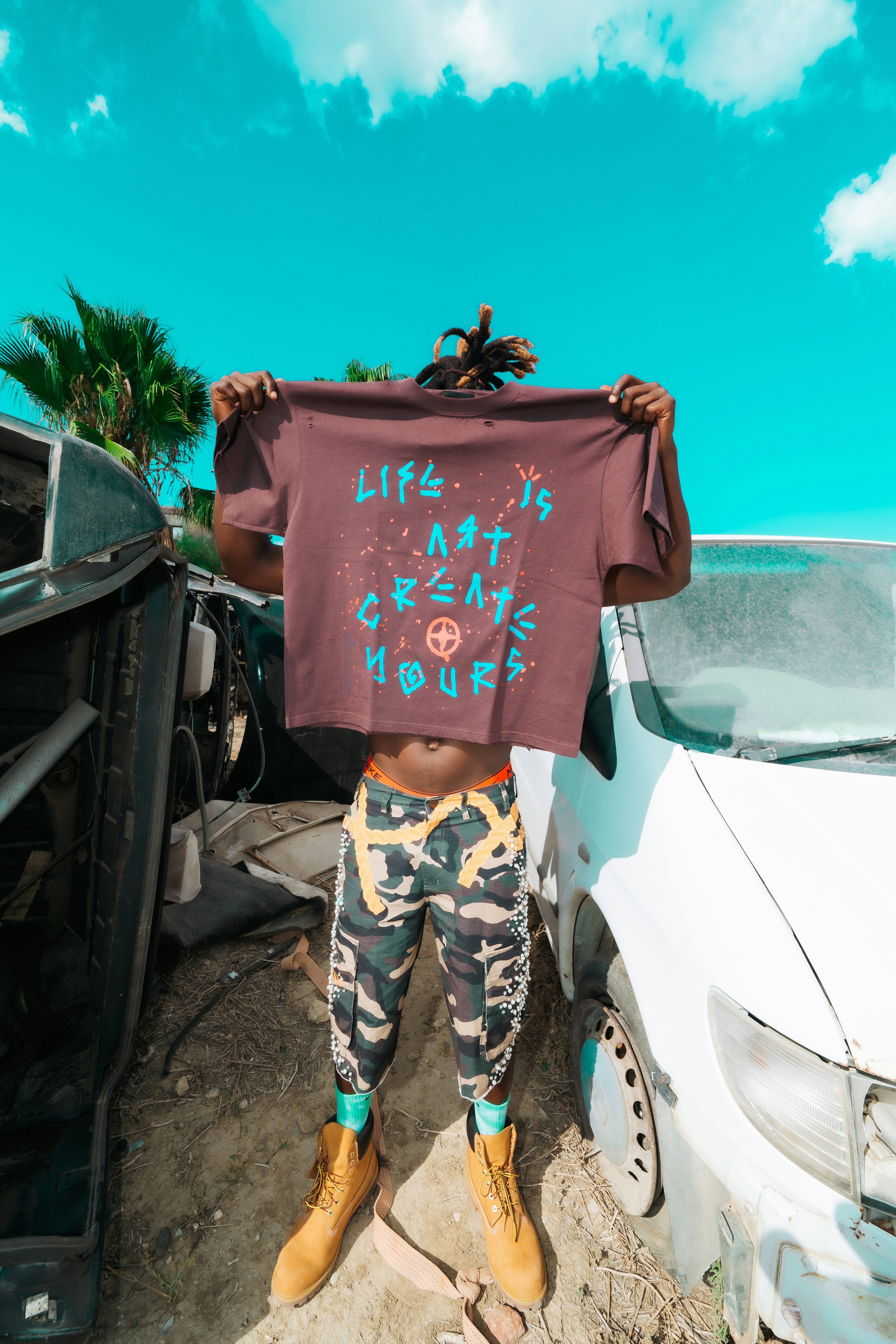 A person holding a brown t-shirt with blue text in front of their face