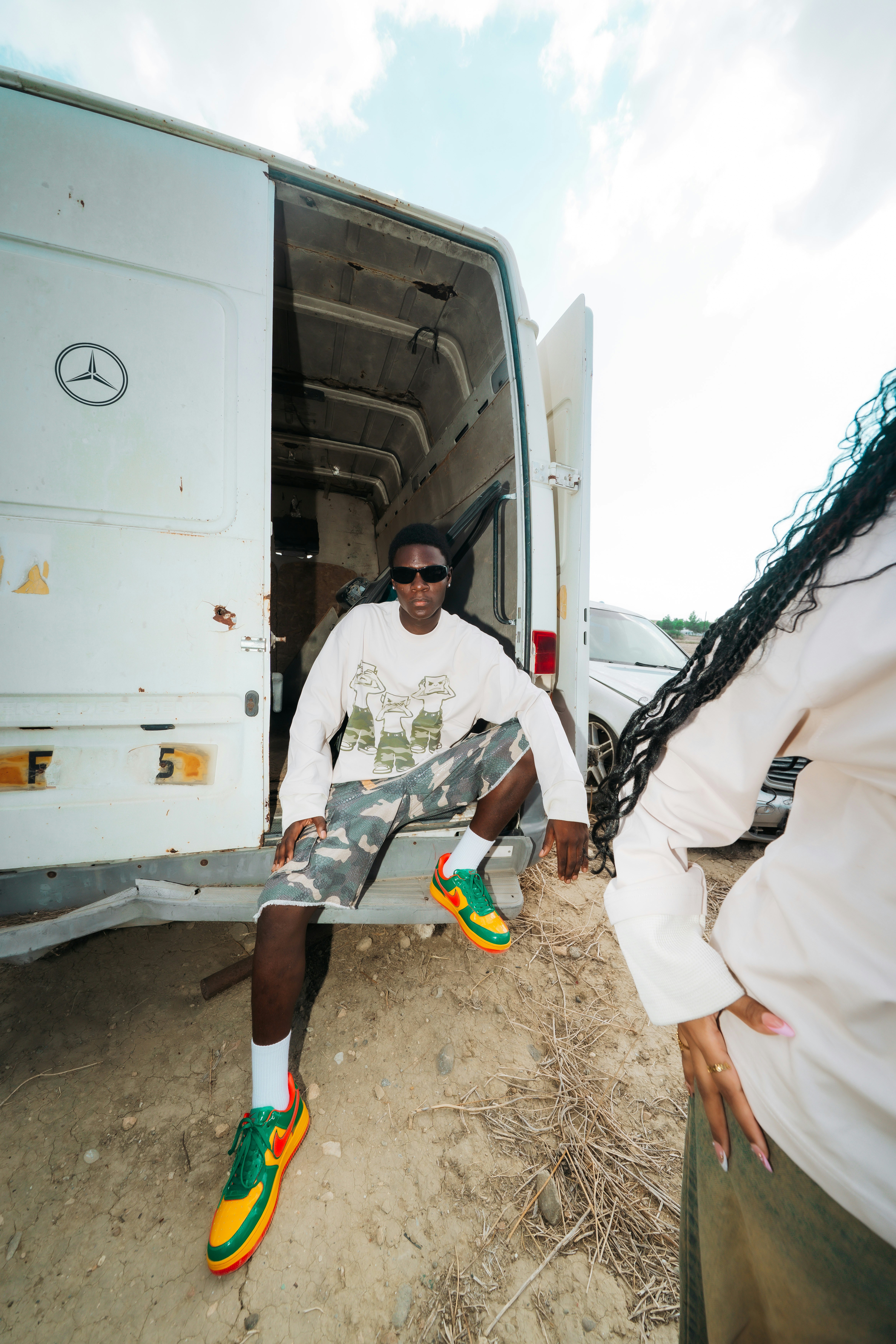 A person in sunglasses and a graphic sweatshirt sitting in a white van