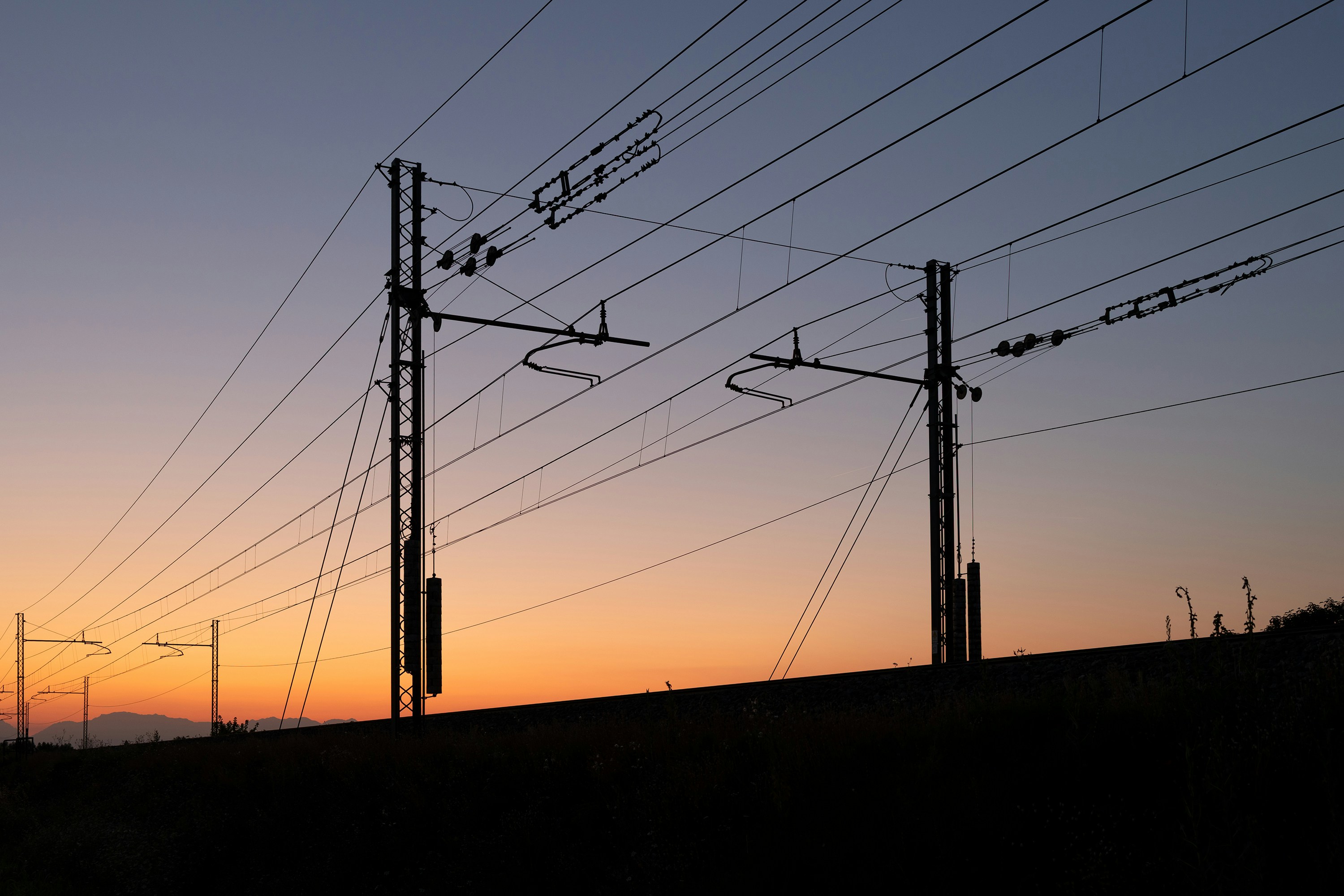 Railway overhead wires and poles silhouetted at sunset