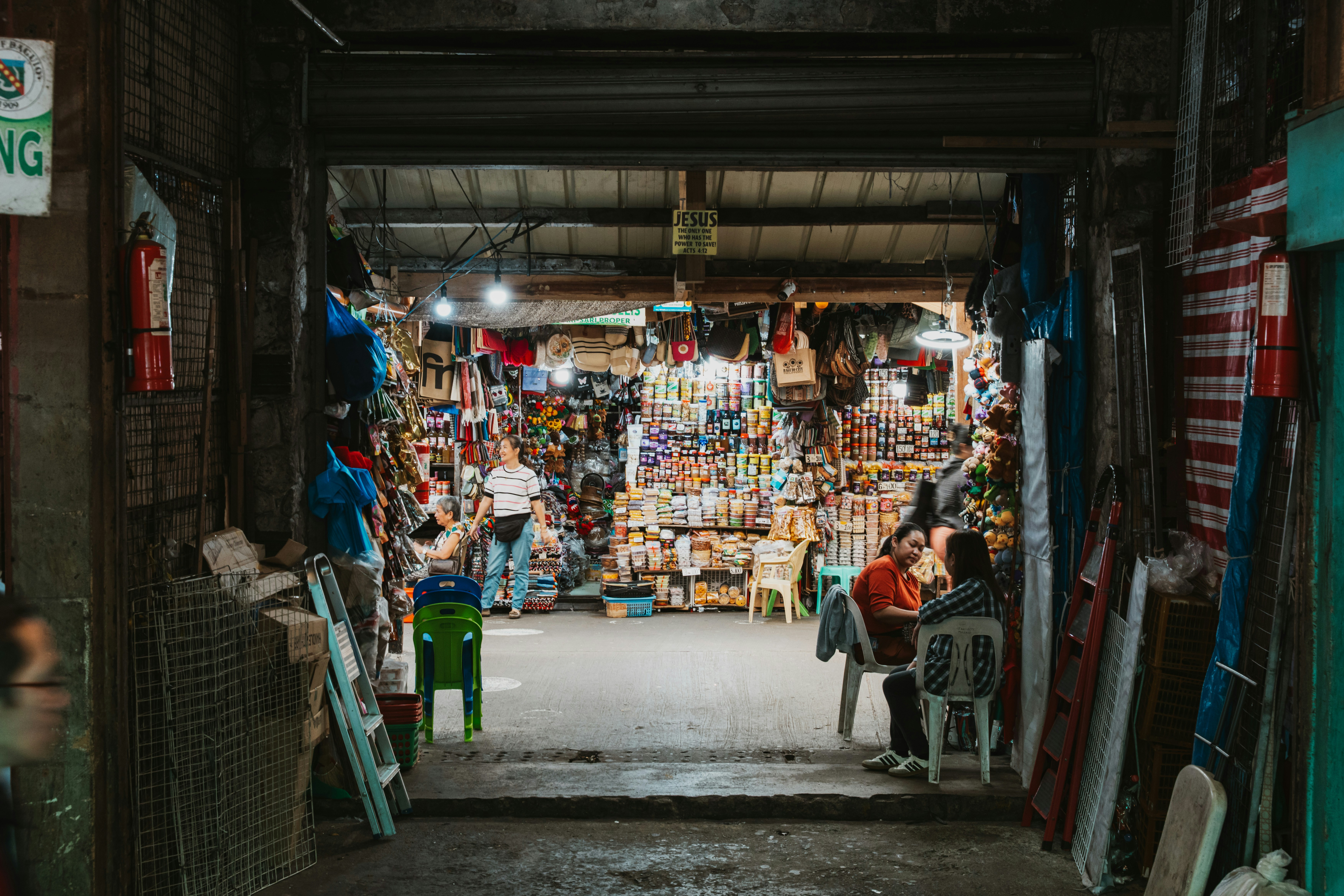People sitting and standing inside a small shop filled with various goods