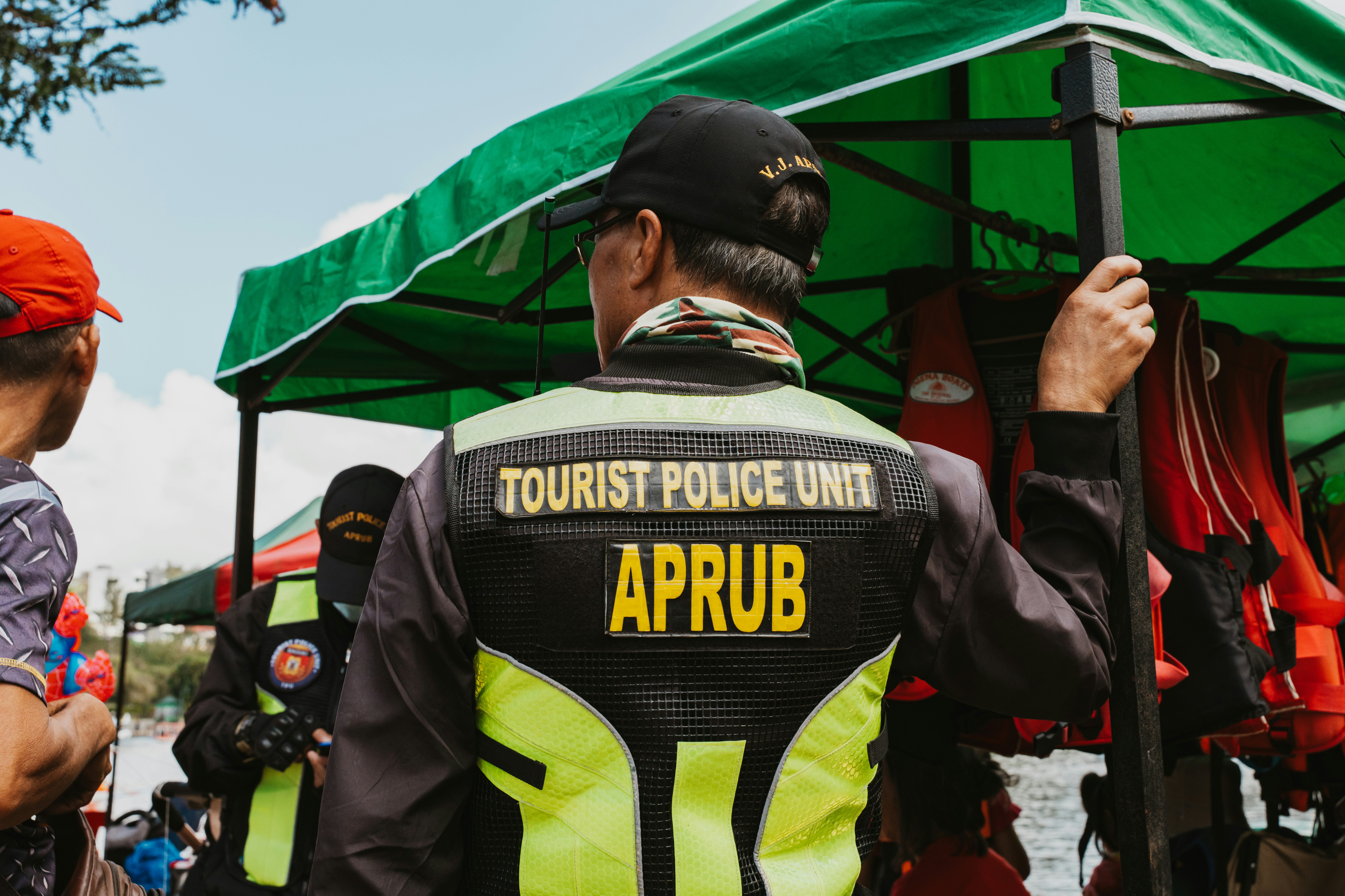 A tourist police officer in a high-visibility vest standing under a green canopy