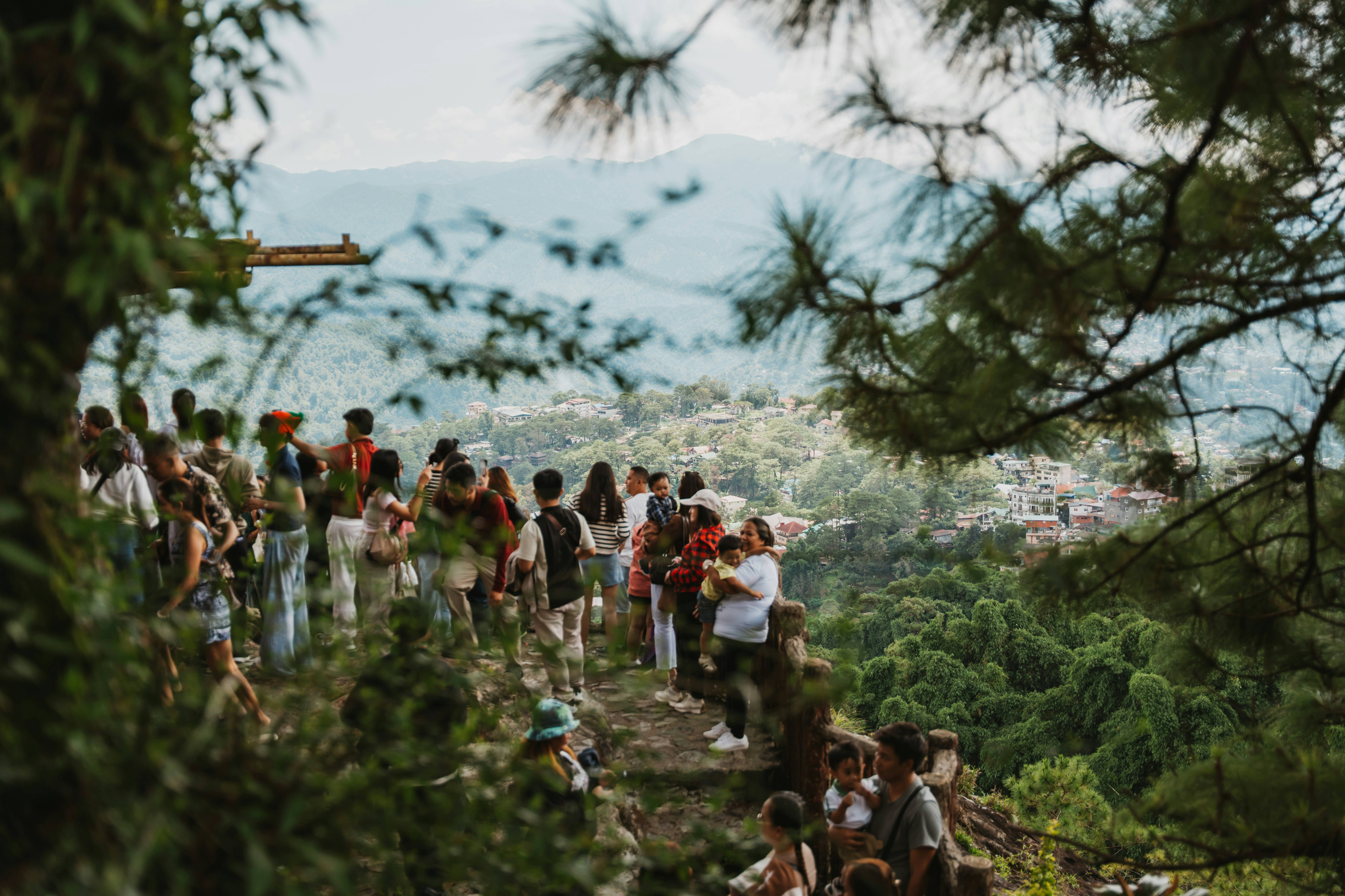 A group of people on a rocky overlook above a forested mountain valley