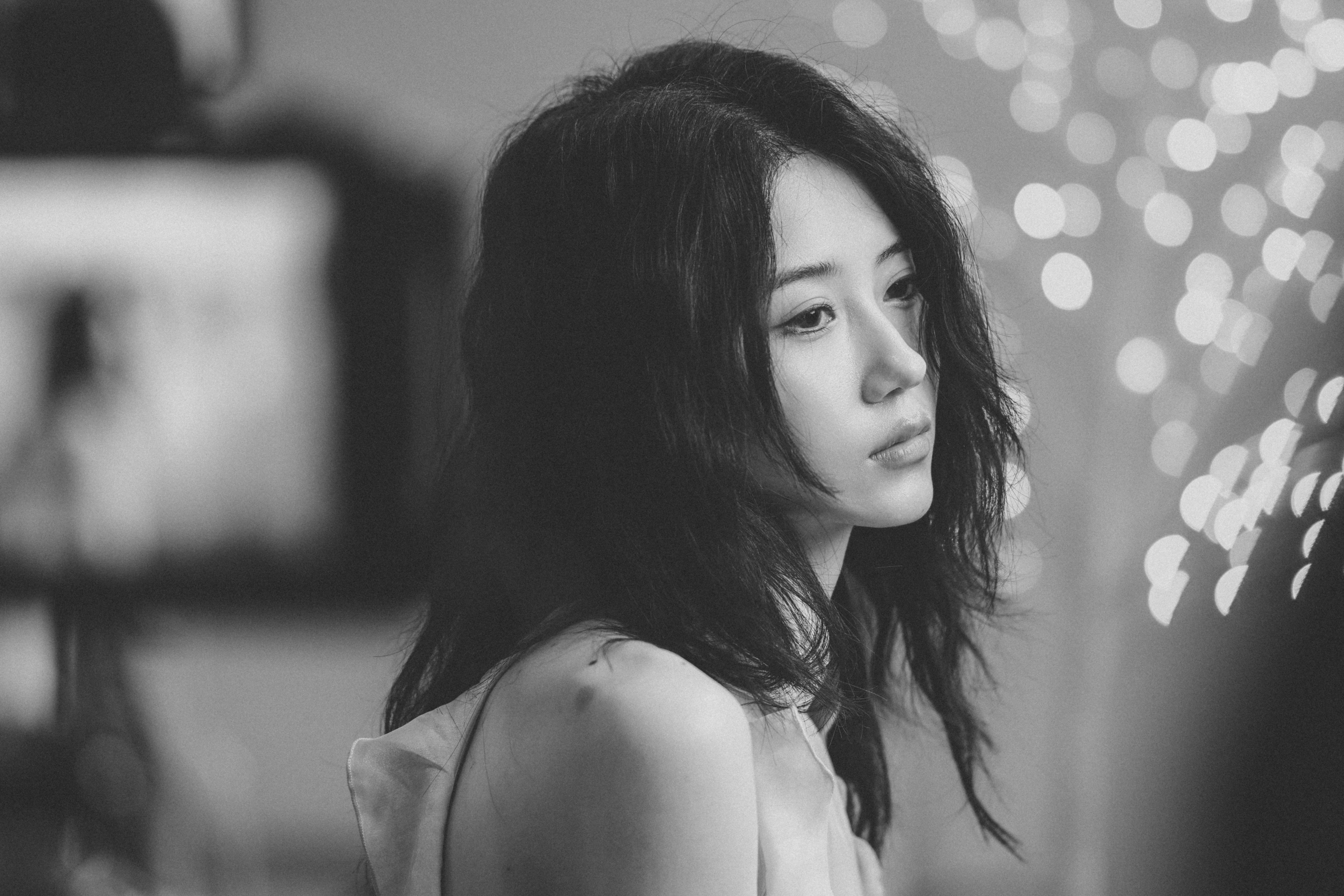 A woman with dark hair in a black and white portrait with bokeh