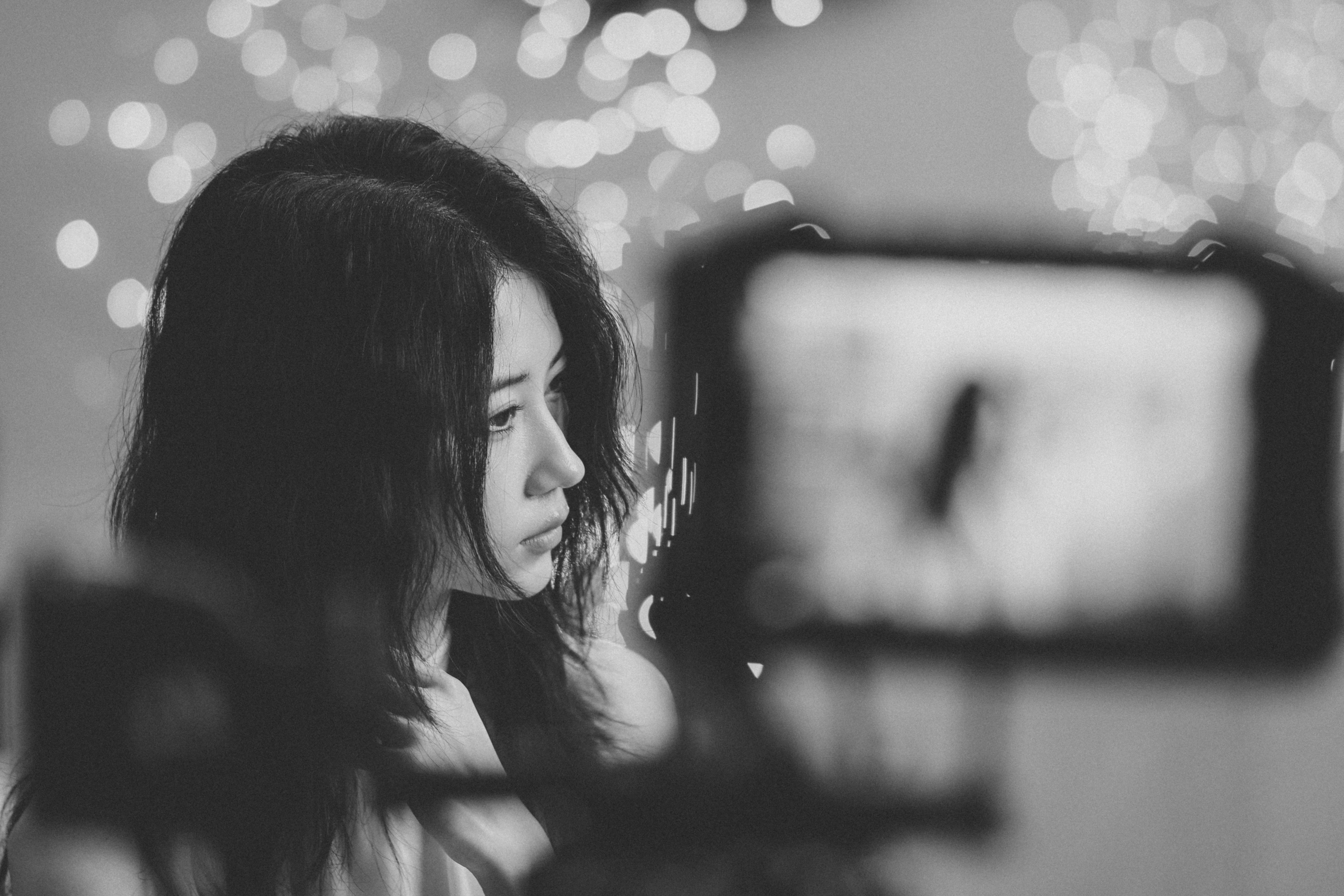 A woman with dark hair in profile before a background of bokeh lights