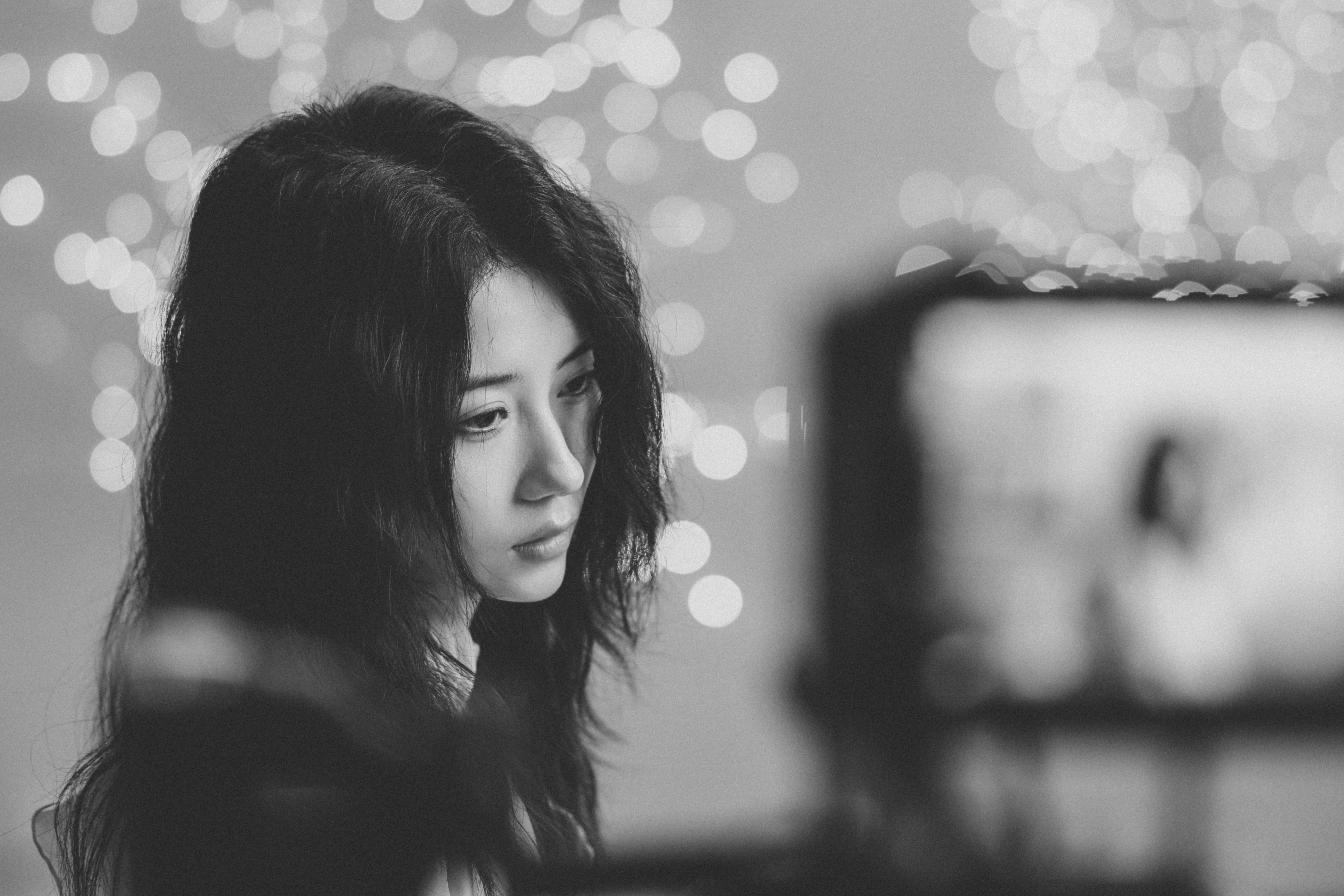 A woman with long dark hair against a background of soft bokeh lights