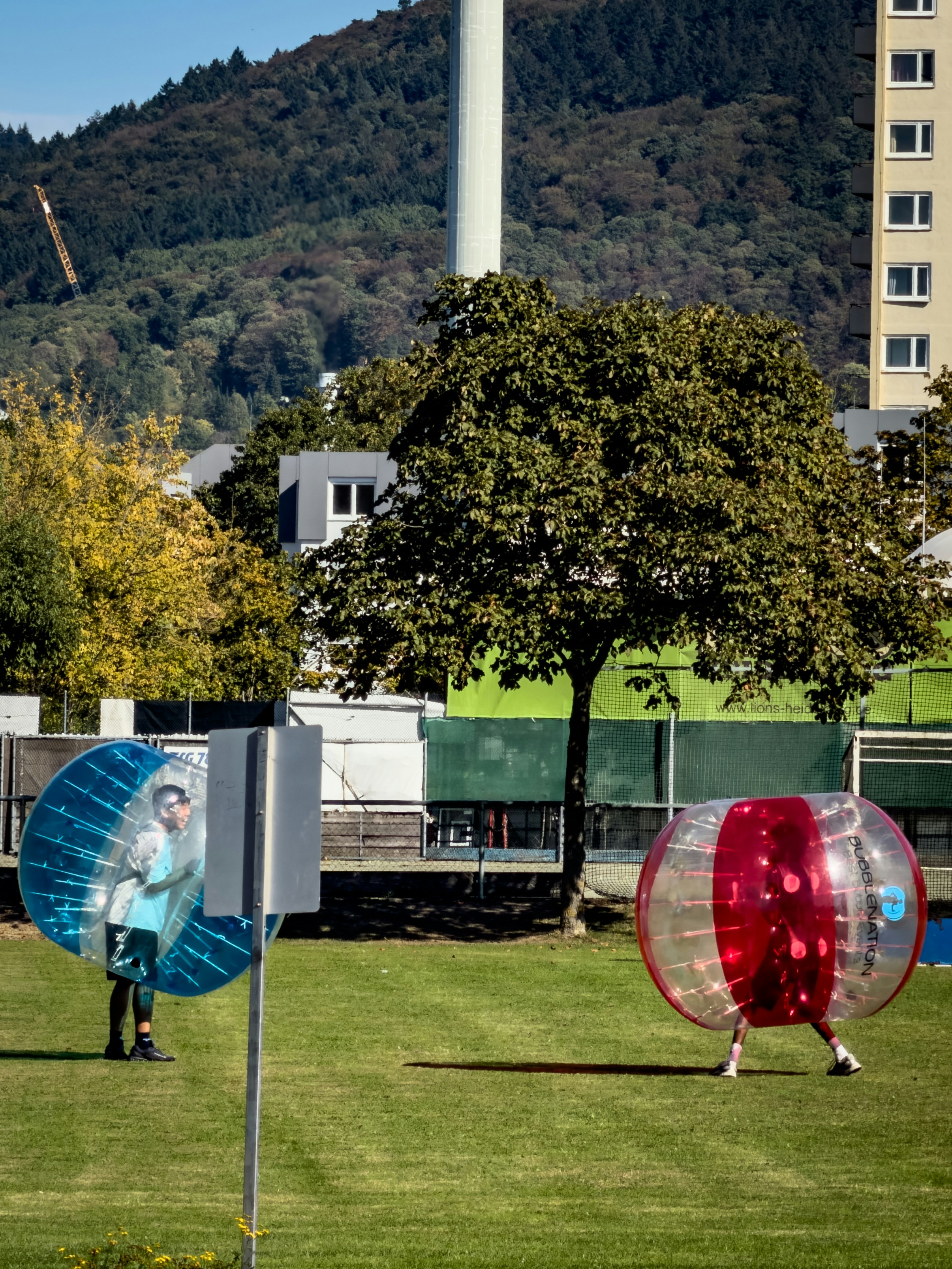 Deux personnes en combinaisons bulles gonflables jouant sur un terrain d’herbe vert
