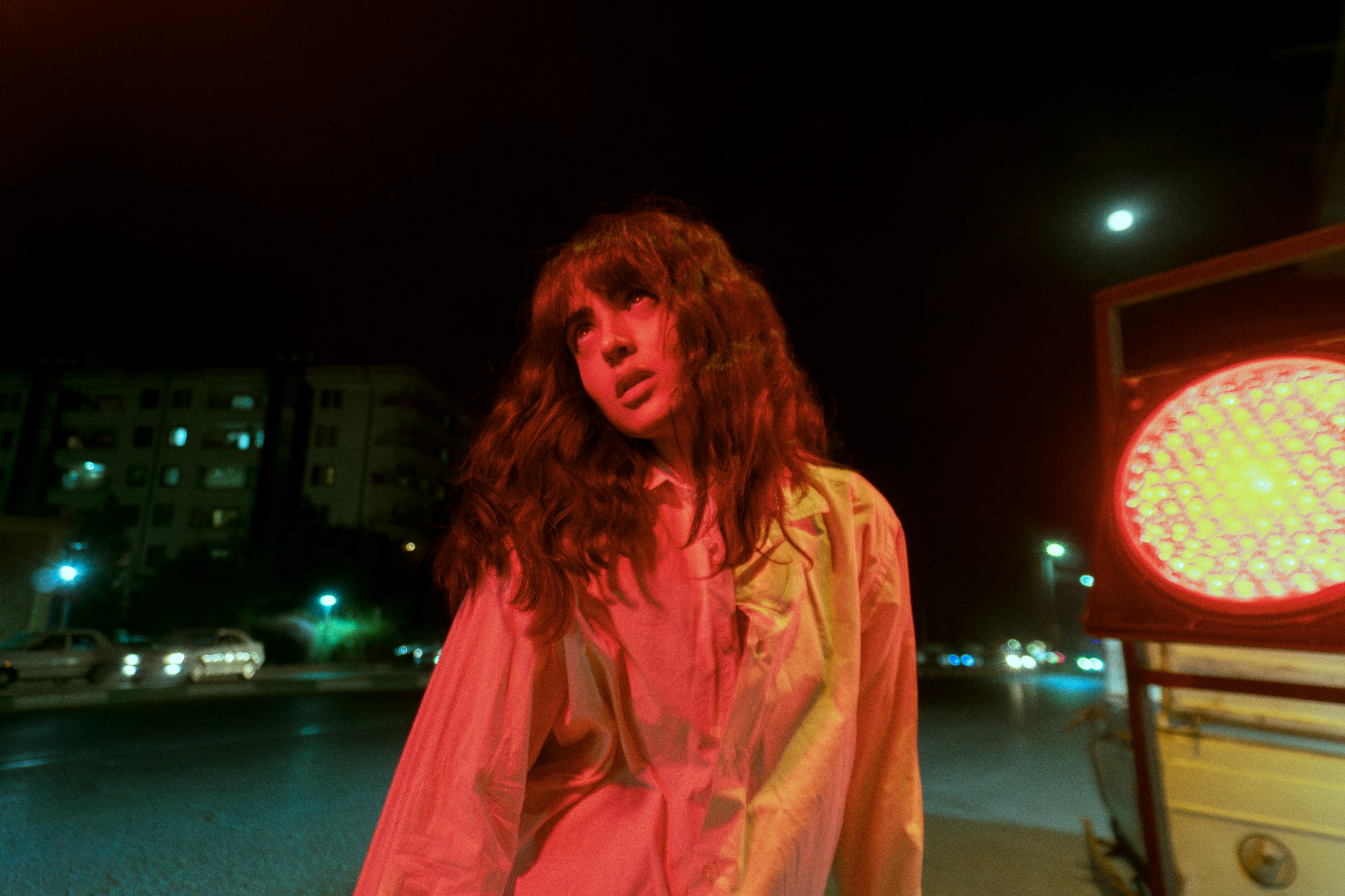 夜の明るい赤い光に照らされた白いシャツの女性