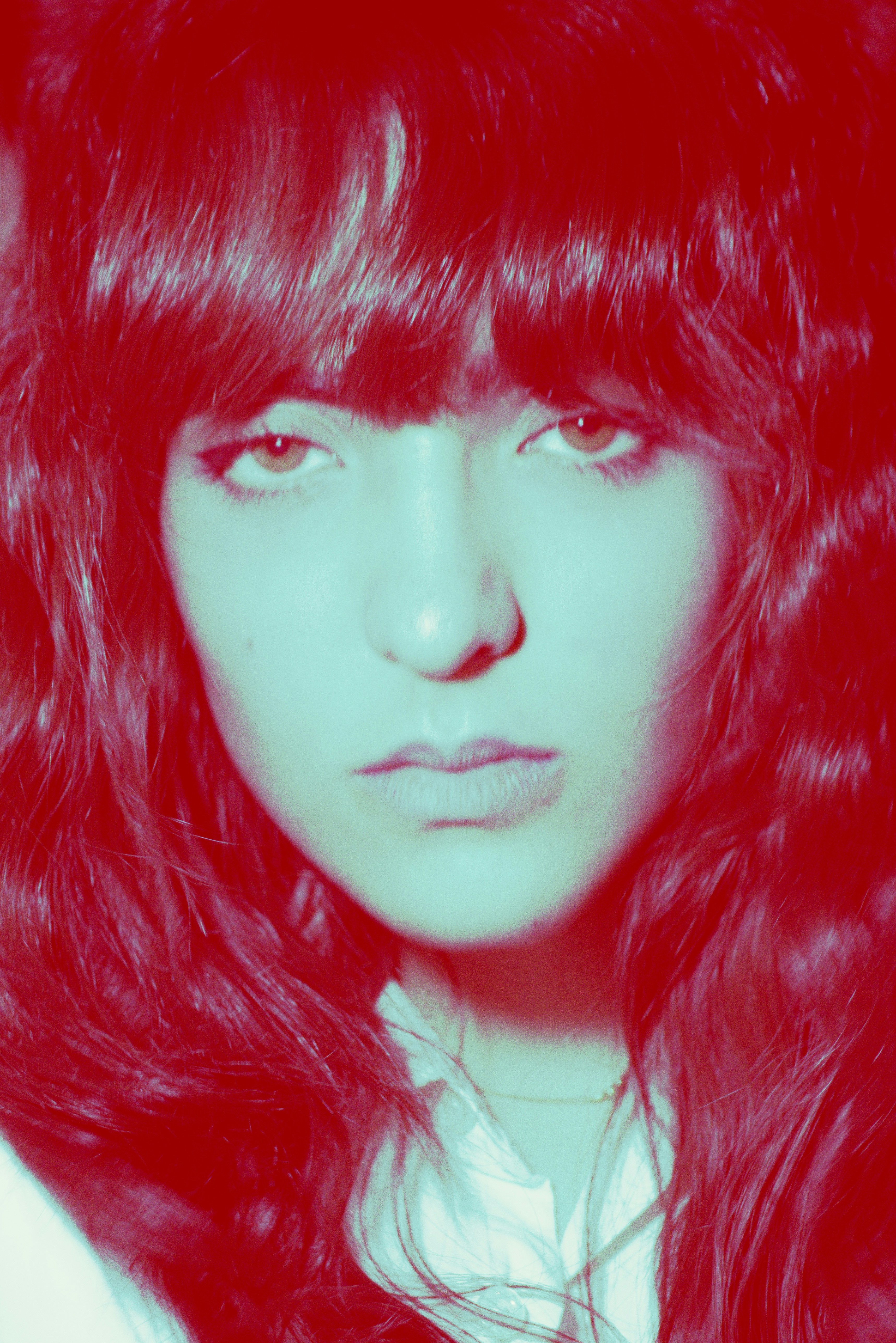A woman with long wavy hair under intense red and cyan lighting