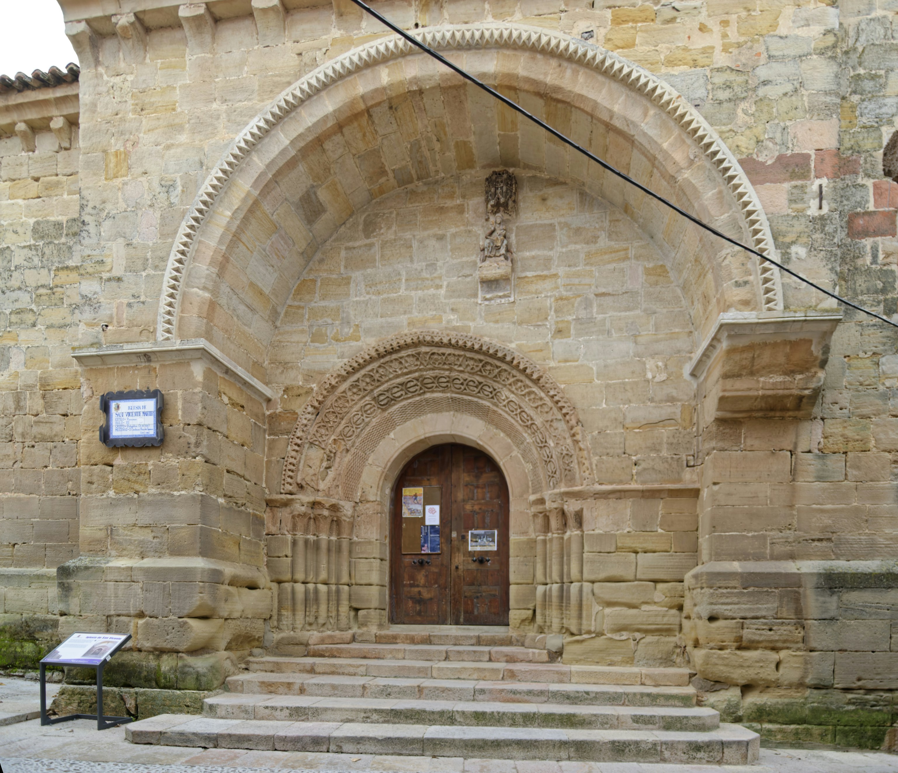 A Romanesque stone arched doorway with intricate carvings above a wooden door