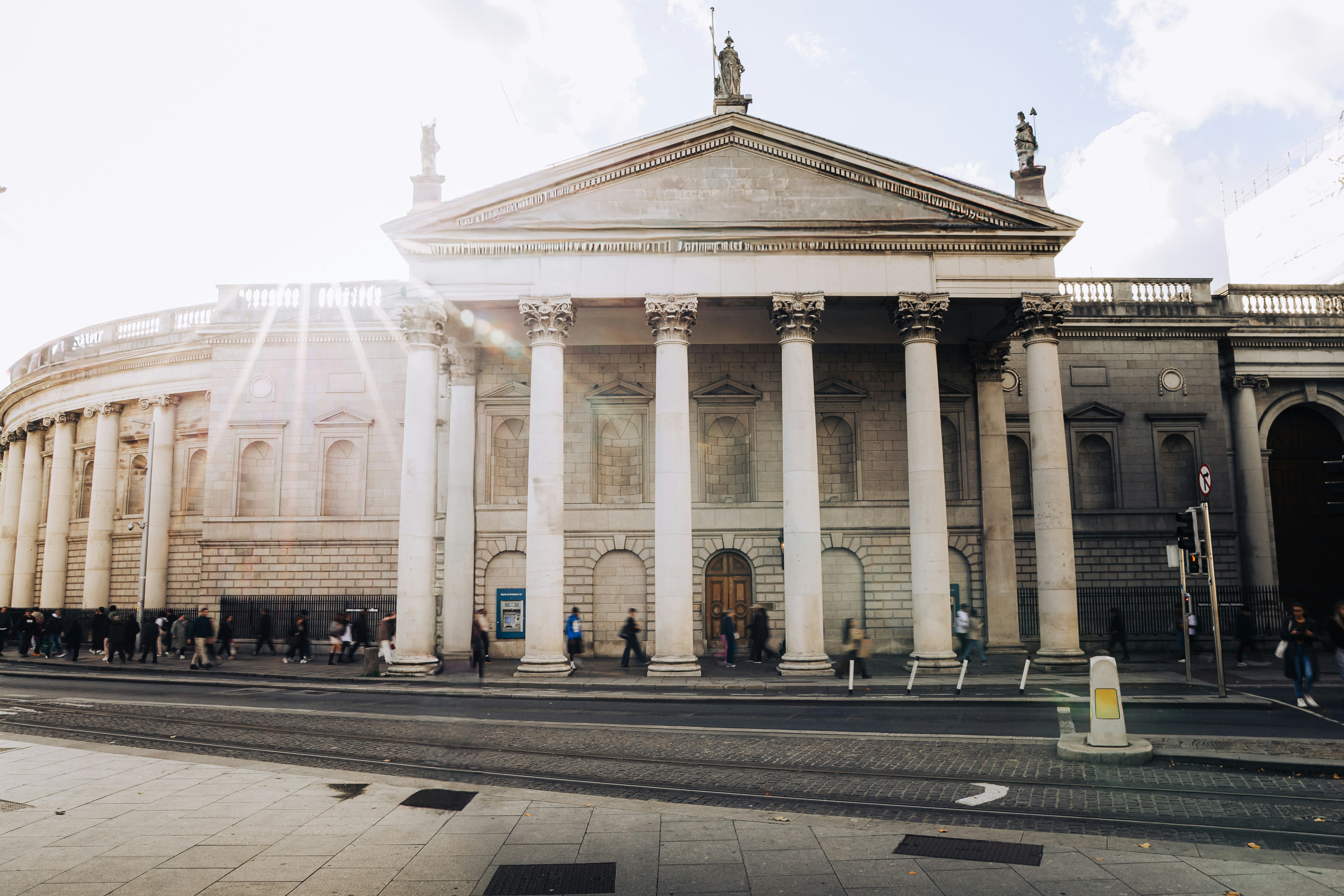 People walking past the neoclassical Bank of Ireland building in Dublin