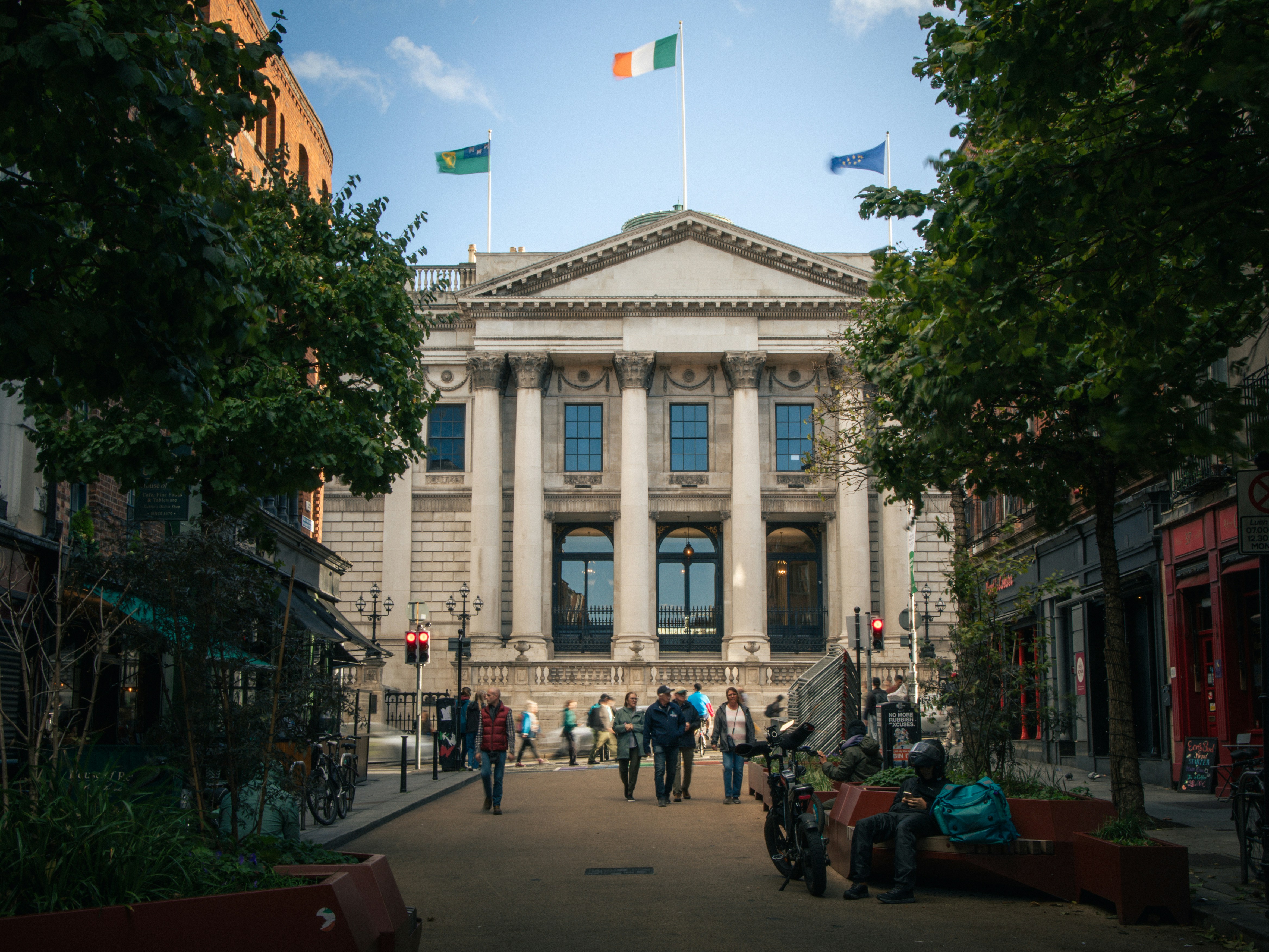 People walking on a pedestrian street toward the neoclassical Bank of Ireland in Dublin