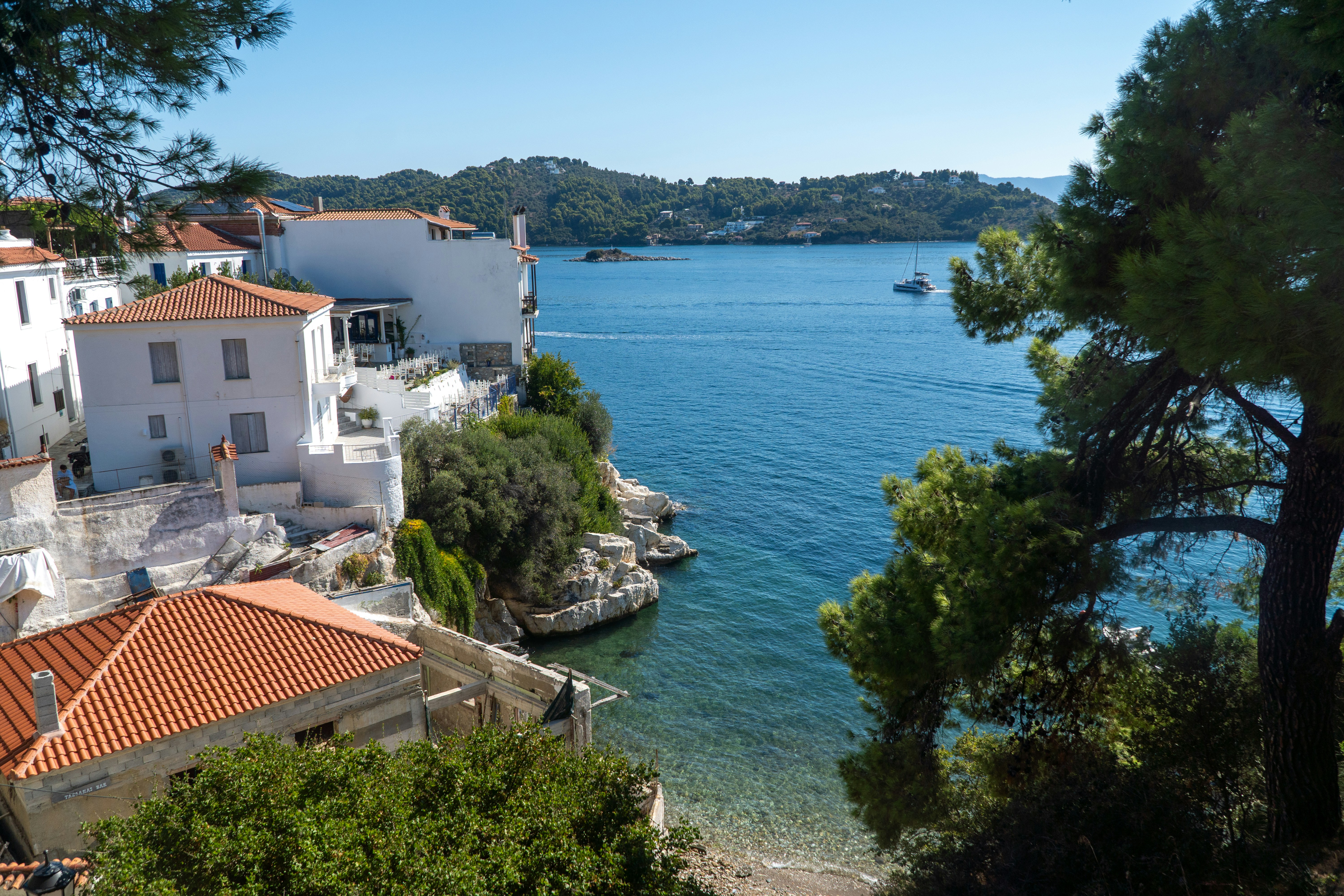 White buildings with terracotta roofs on a rocky coastline overlooking a blue sea