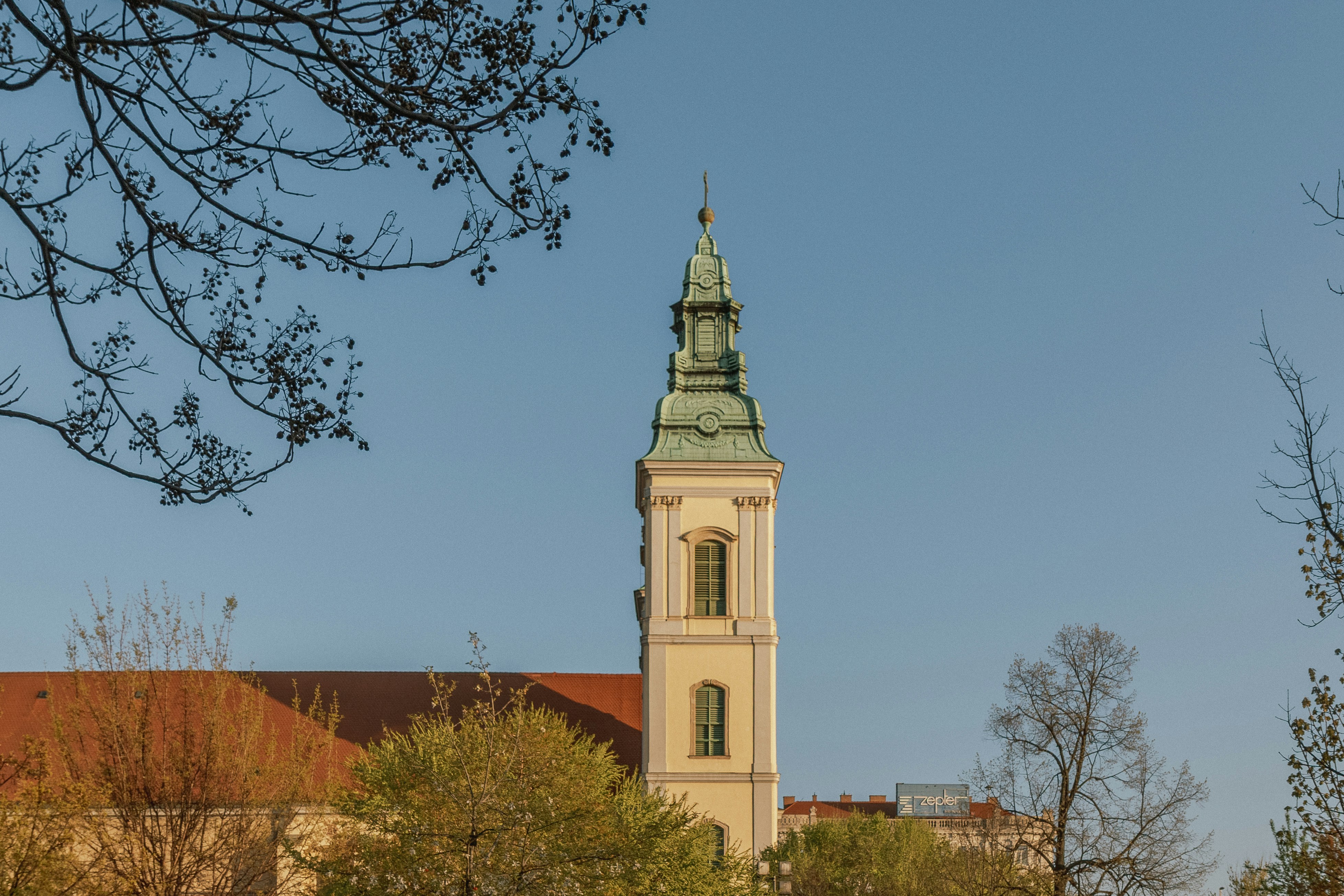 A tall church tower with a green copper roof against a clear blue sky
