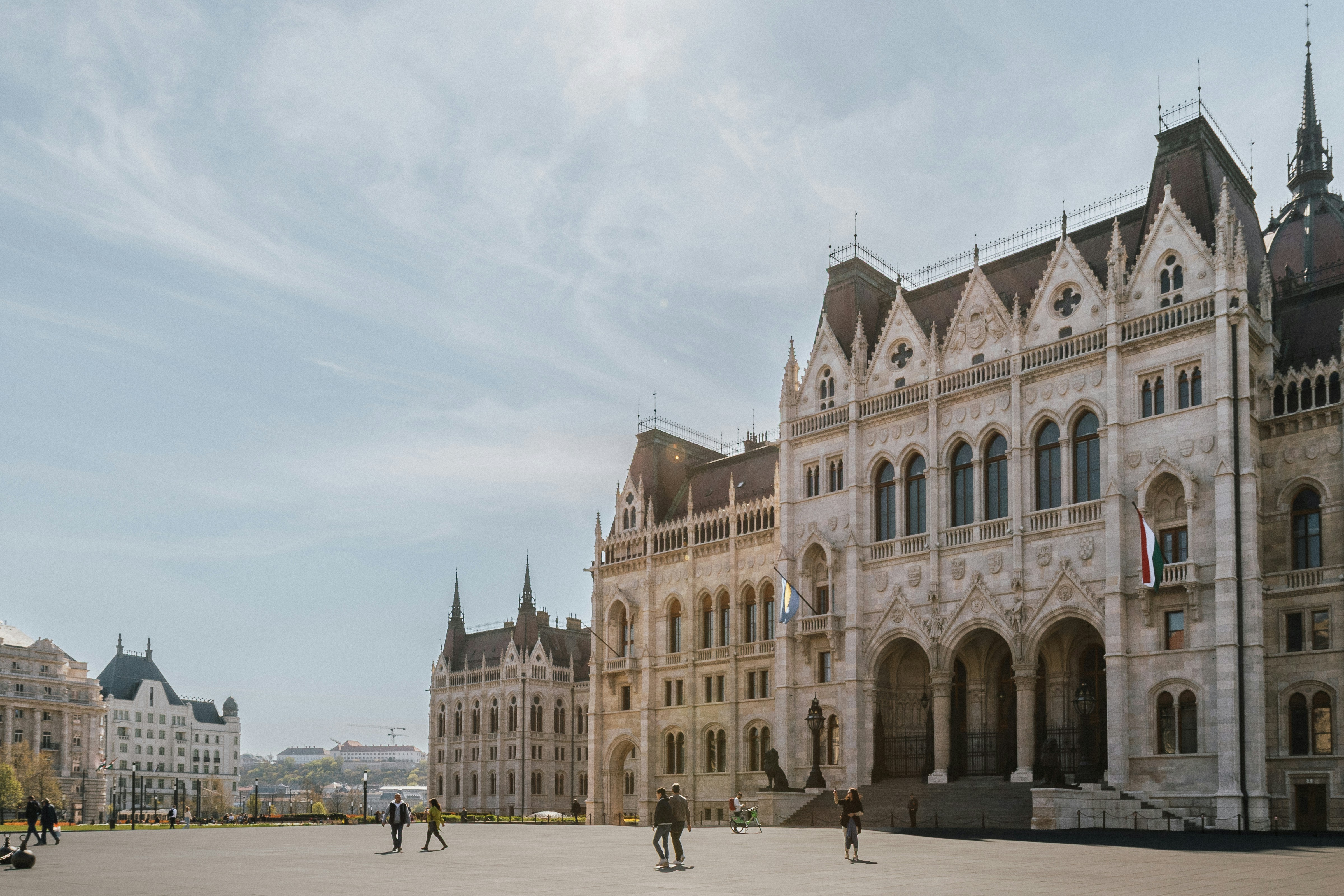 The Hungarian Parliament Building in Budapest with people walking across the large square