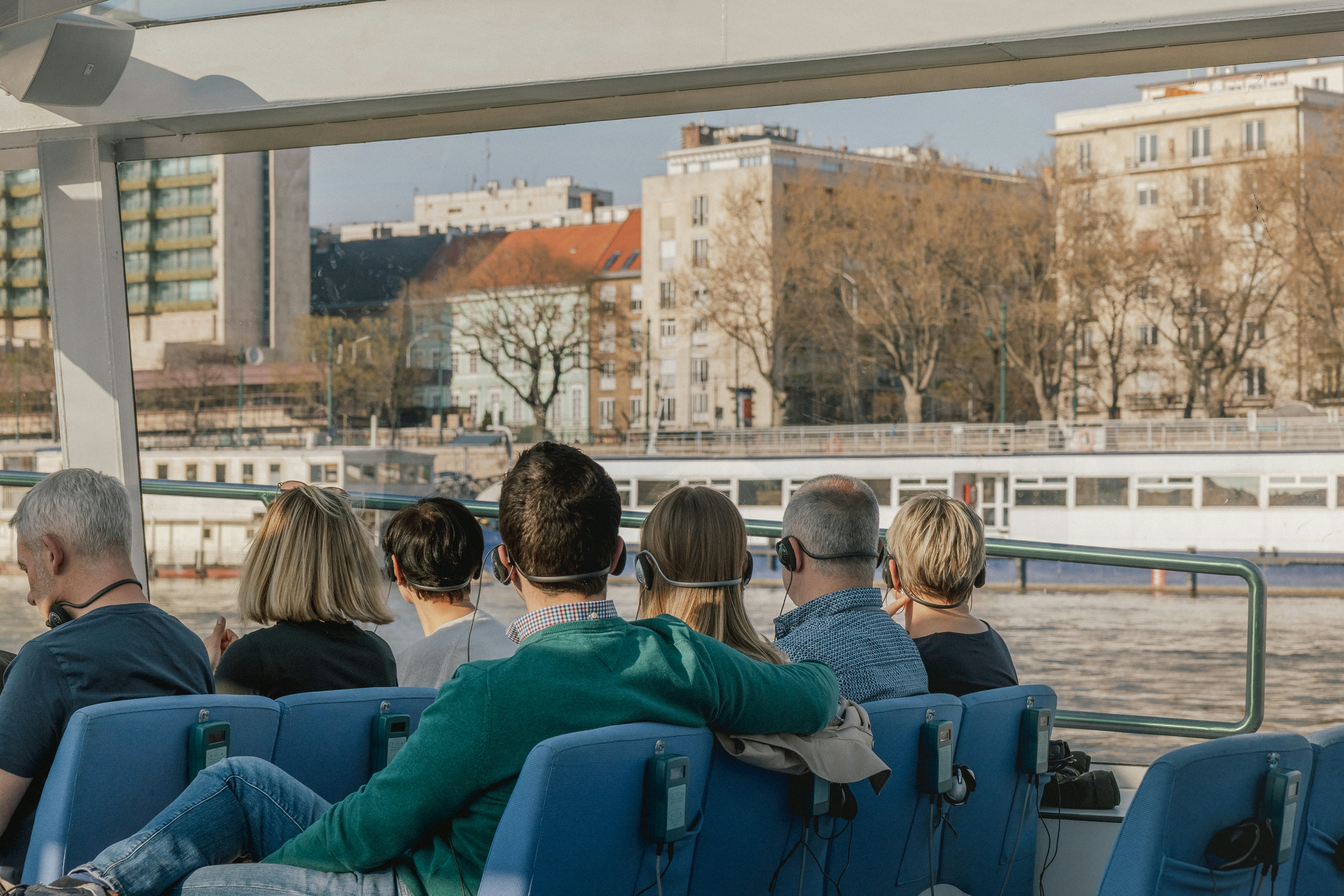 A group of people wearing audio headsets on a boat tour in Budapest