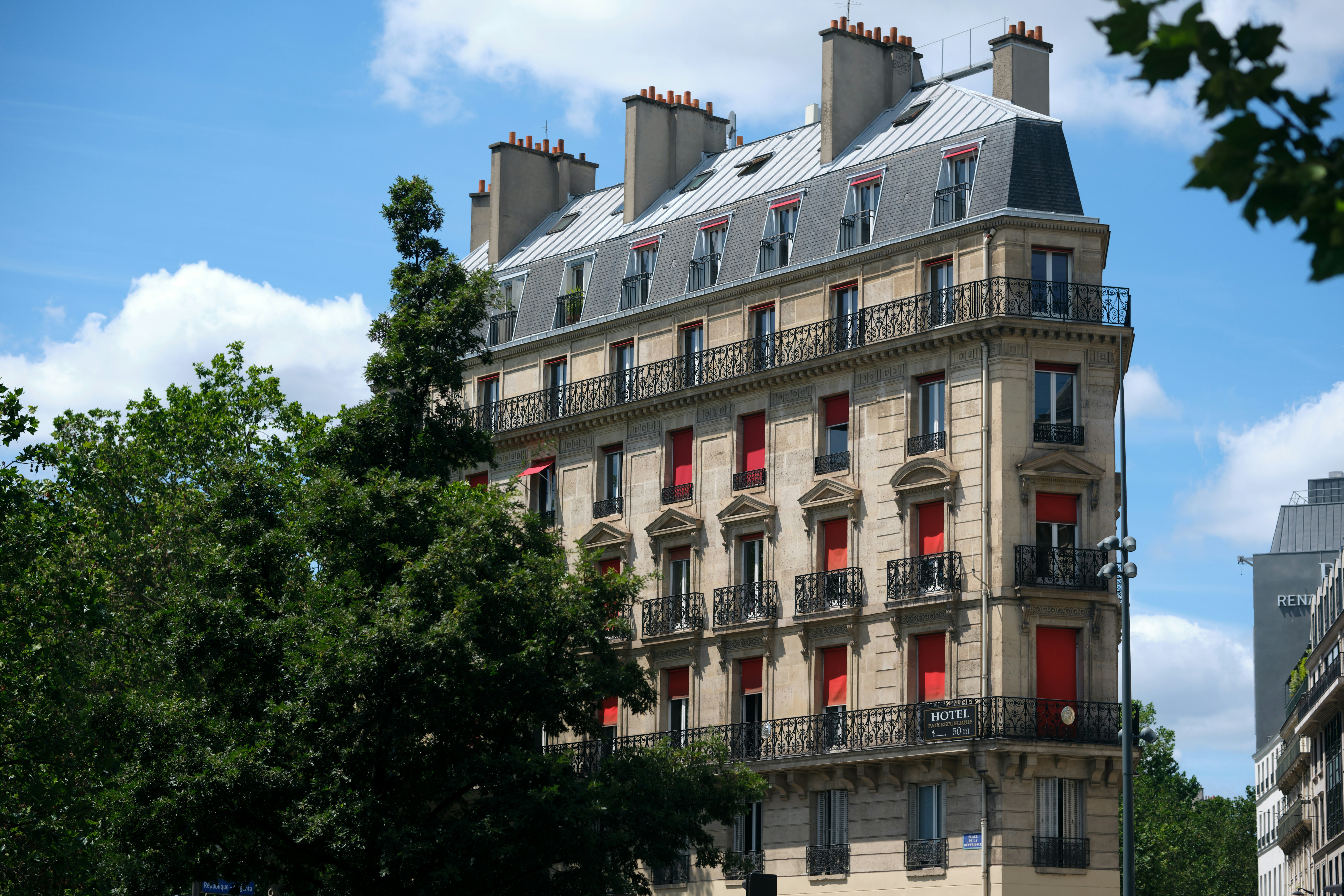 A Haussmann style building with red shutters and wrought iron balconies in Paris