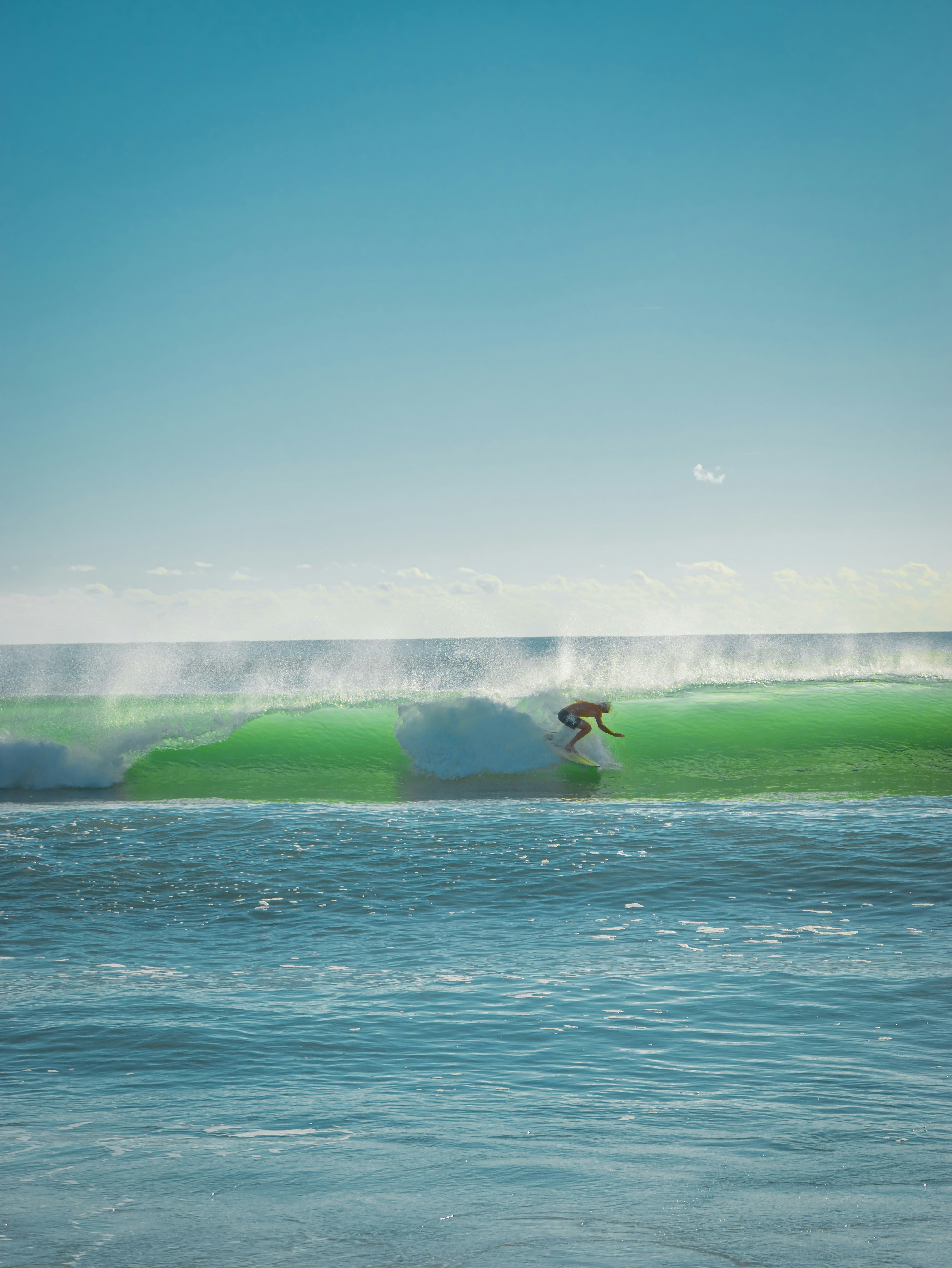 A surfer riding a bright green wave in the open ocean