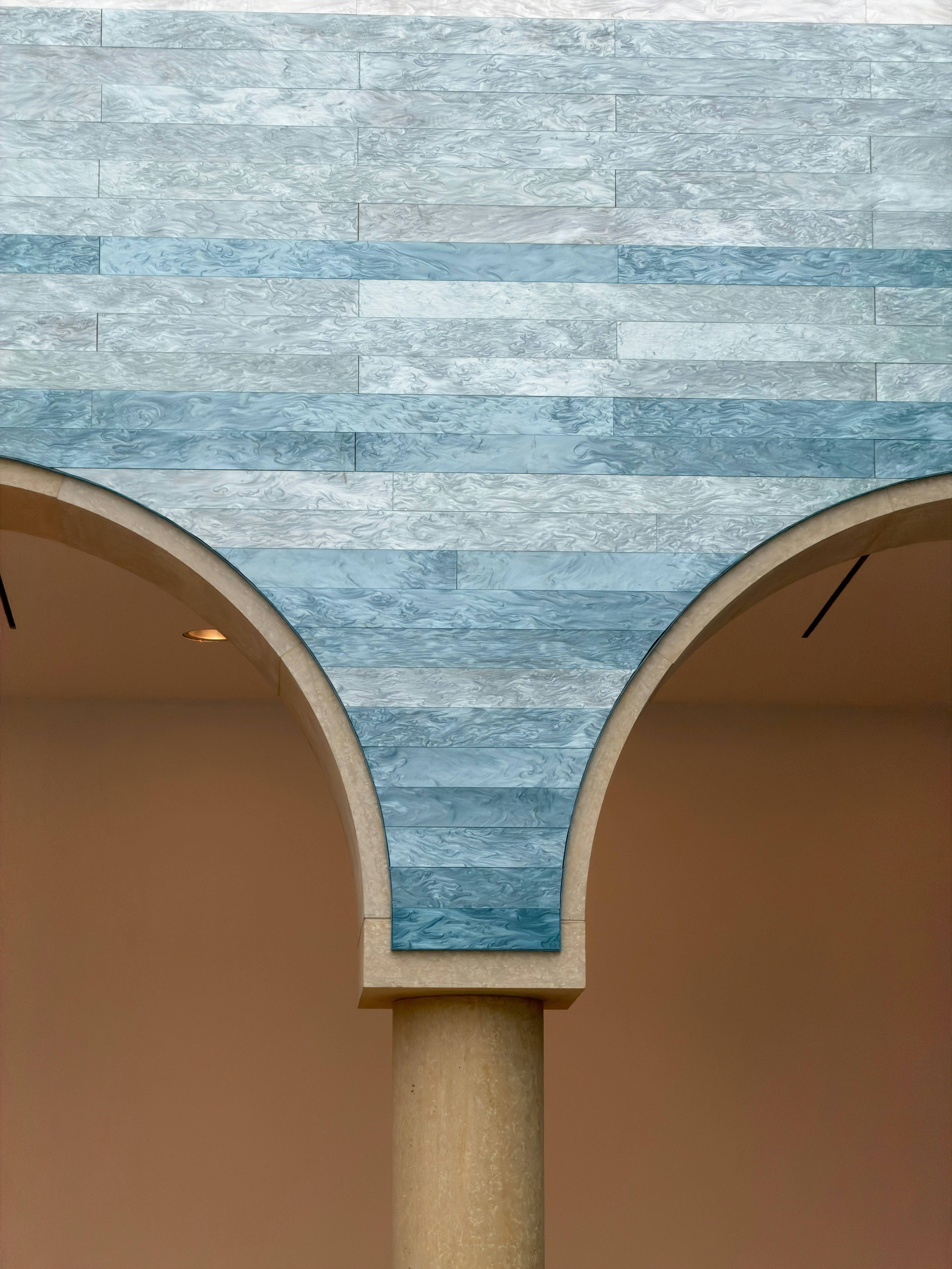 Una colonna in pietra che sostiene due archi con pannelli in piastrelle marmorizzate blu sopra