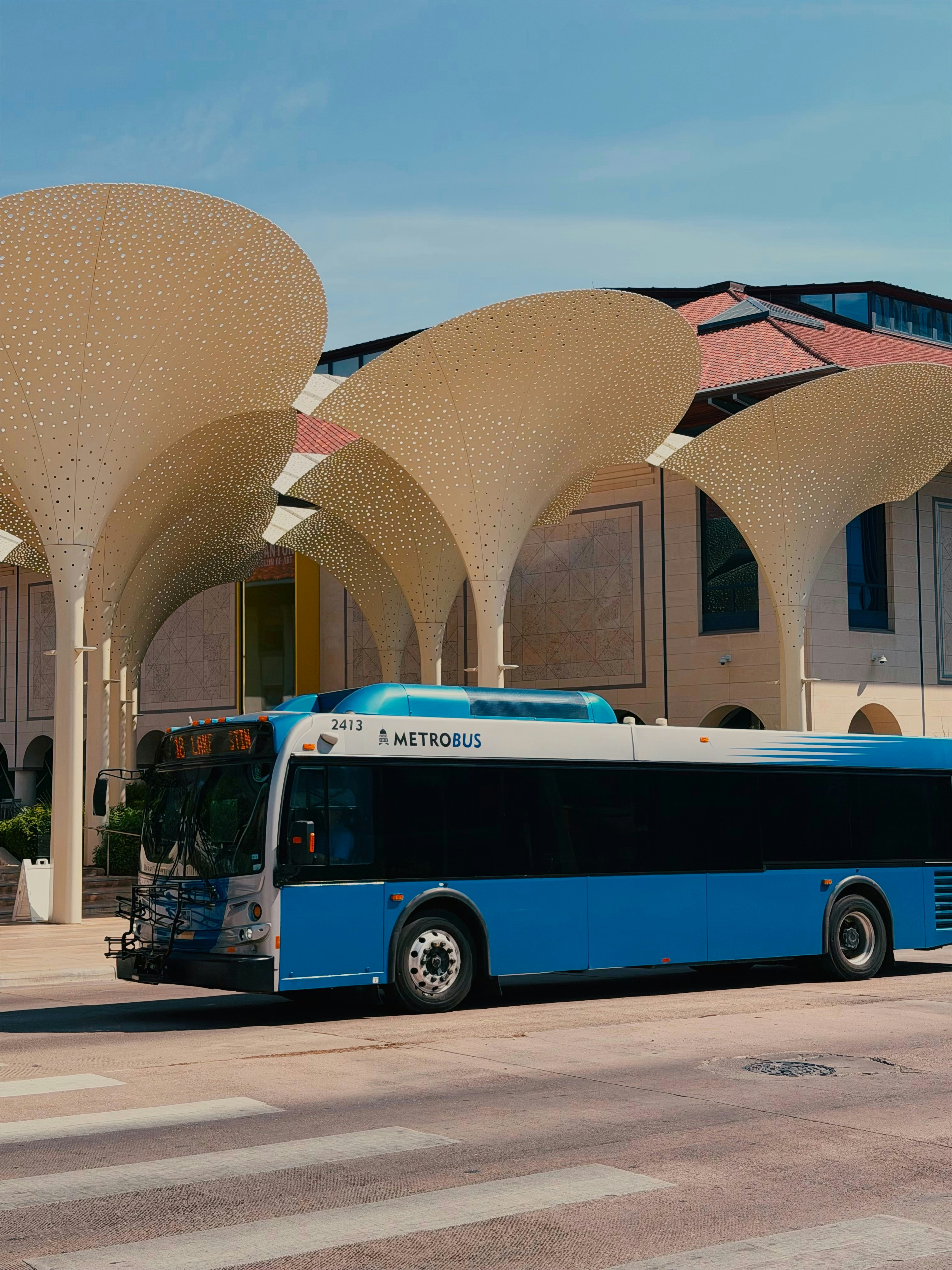 Un Metrobus blu e bianco che passa davanti a grandi tendine scultoree perforate ad Austin