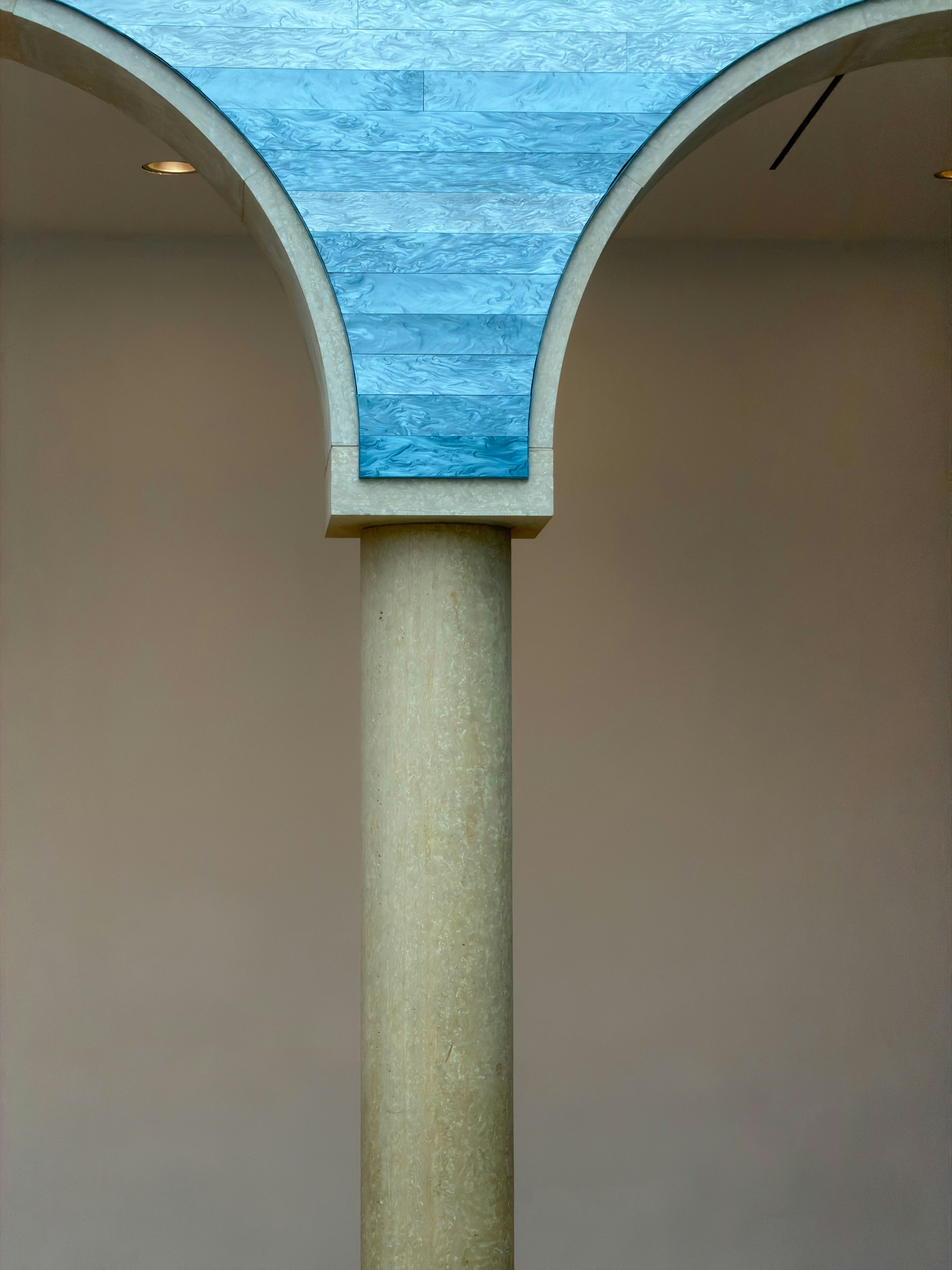 Una colonna di pietra che sorregge un arco marmorizzato blu contro un muro semplice