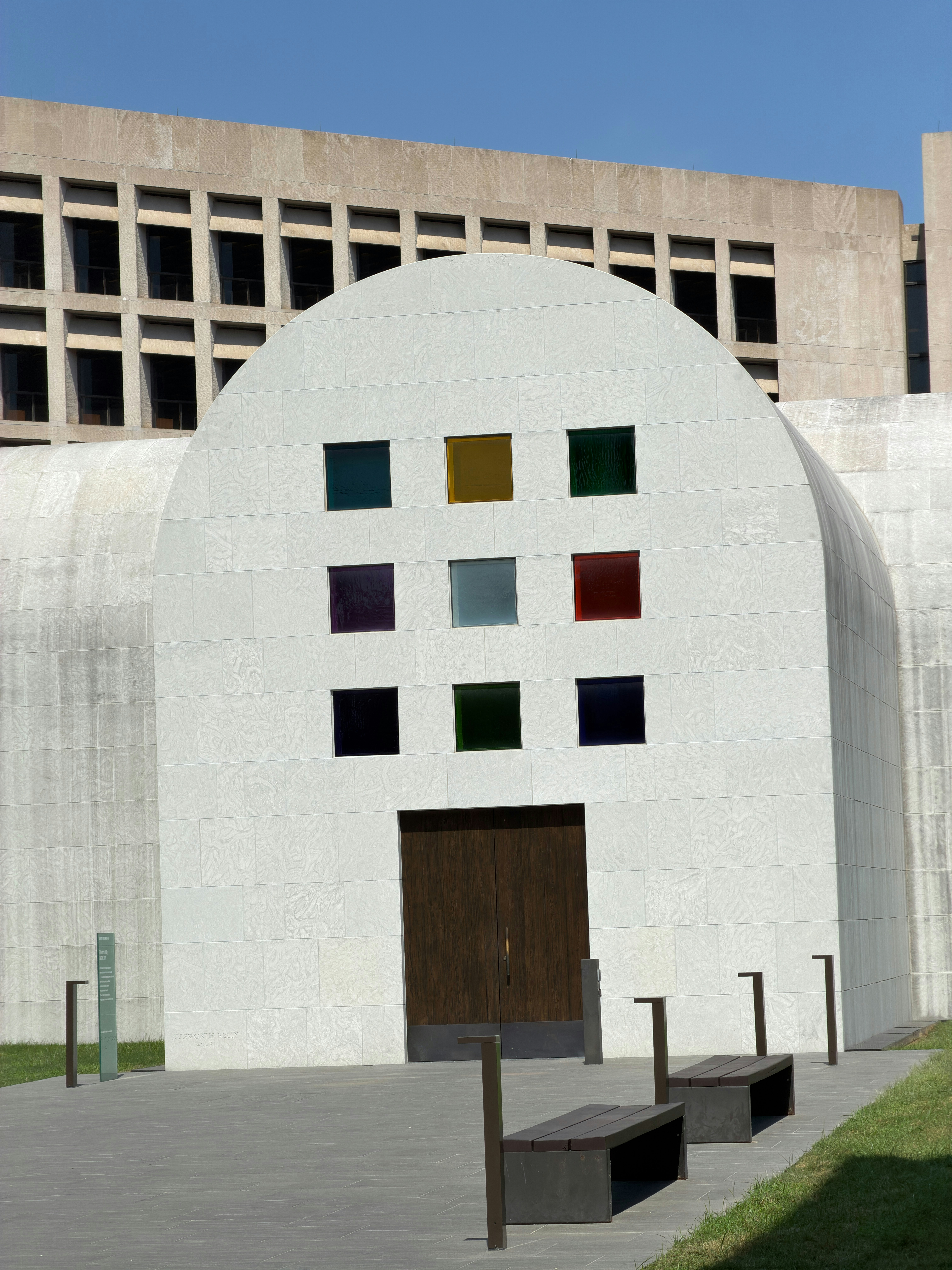 Un edificio in pietra bianca con nove colorate finestre quadrate sopra una porta in legno scuro