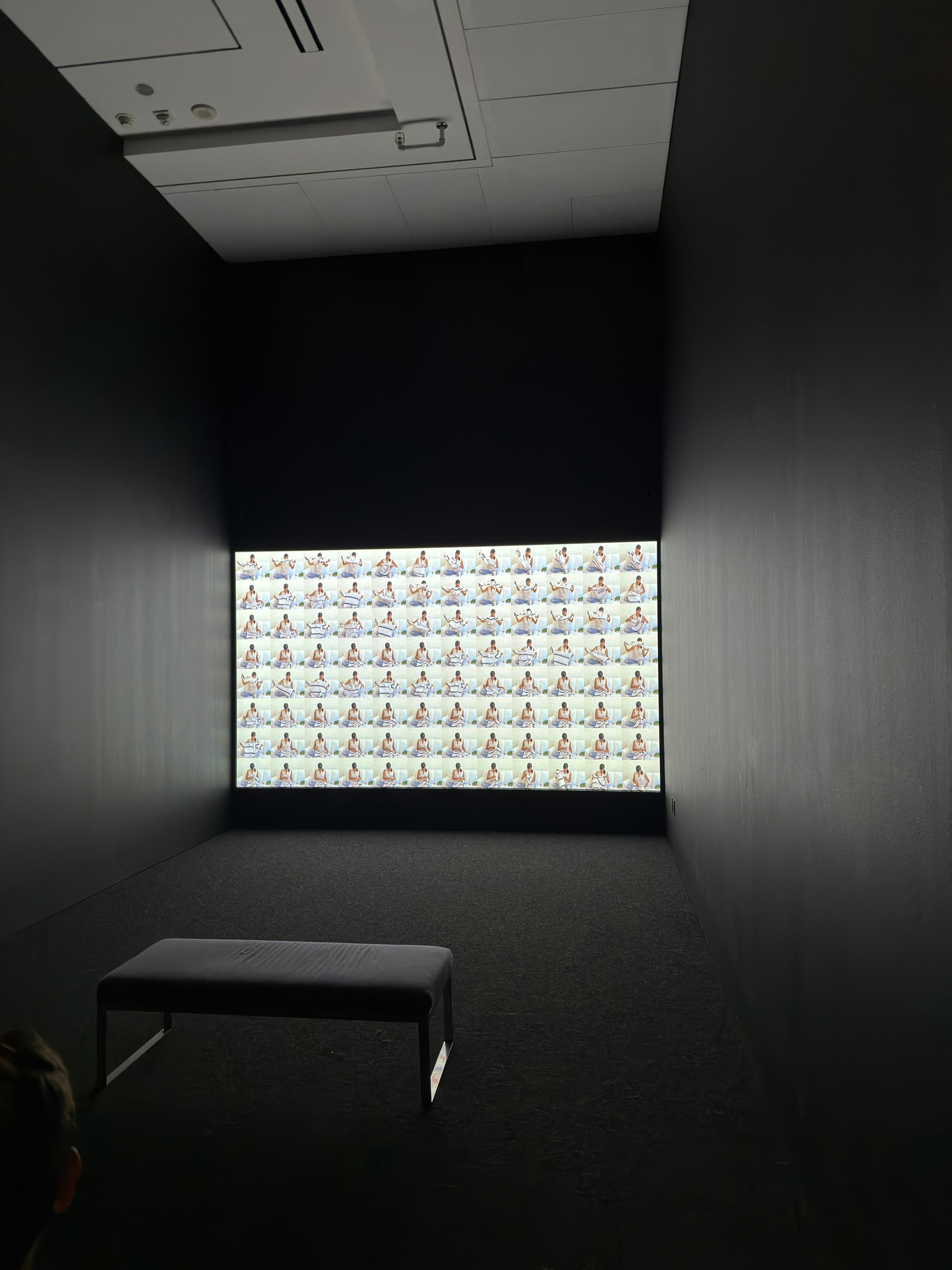 Una griglia di fotogrammi video ripetuti su uno schermo in una stanza buia