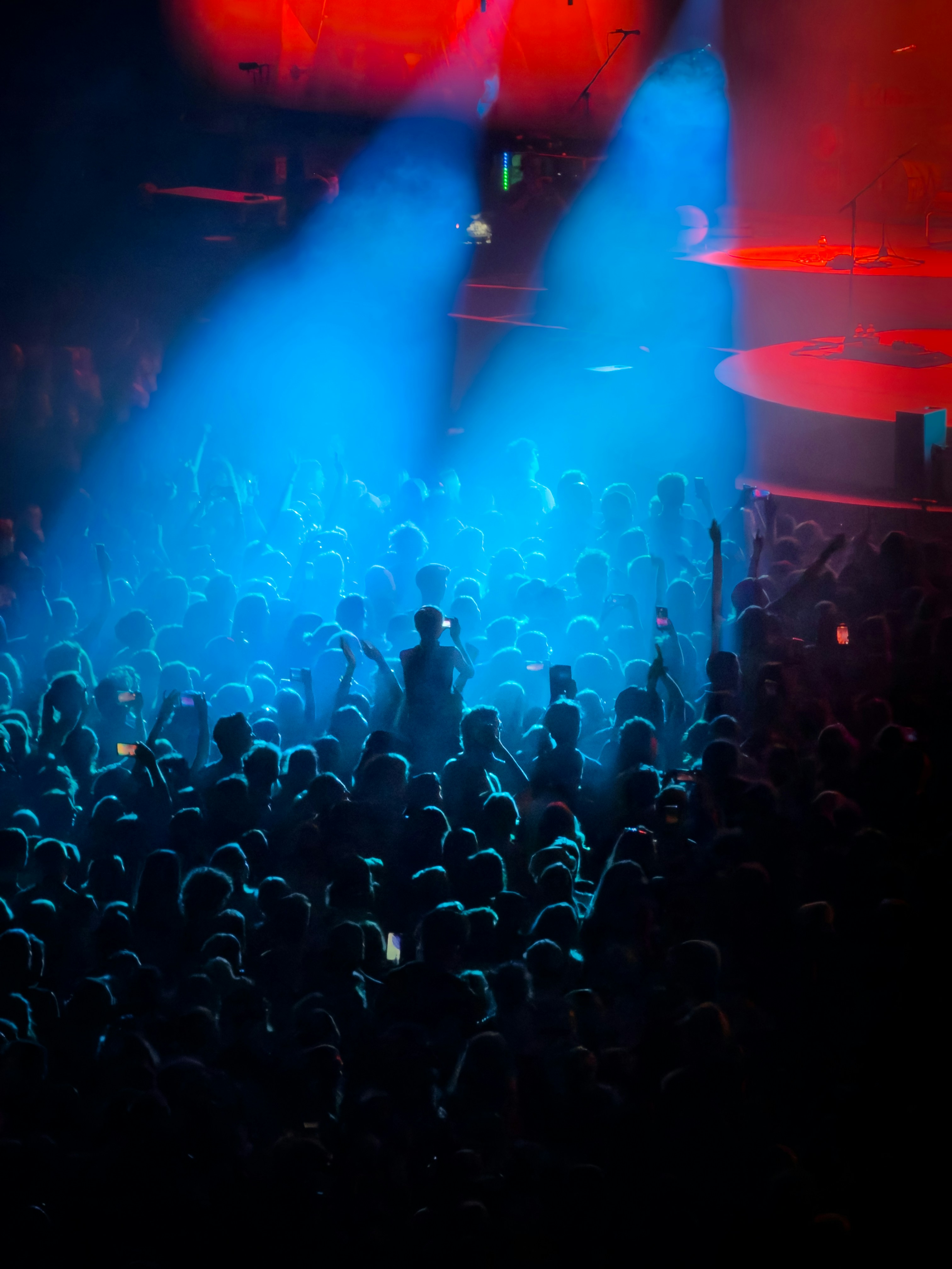A crowd of people at a concert under bright blue and red stage lights