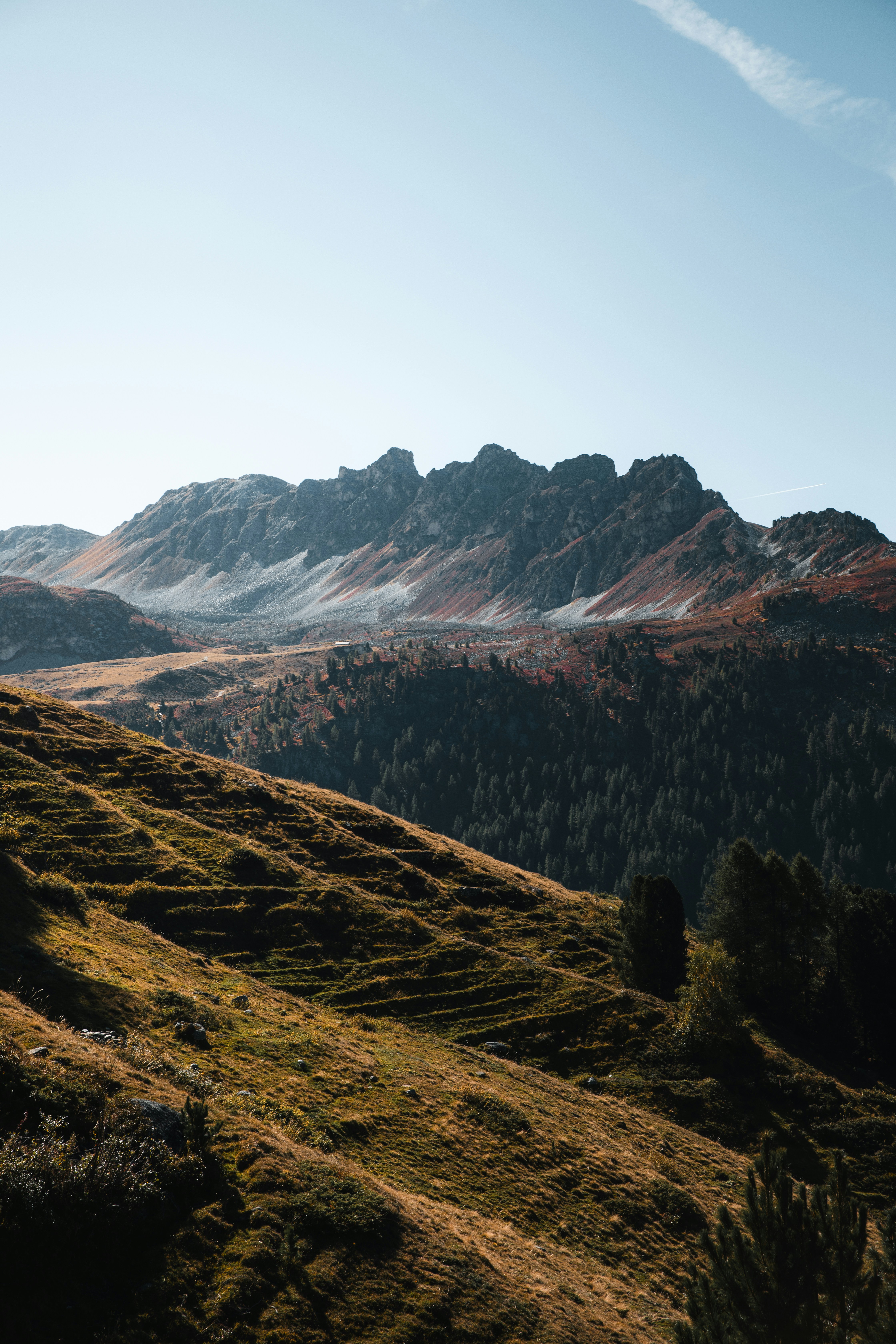 A grassy mountain slope leading to a rugged rocky ridge under a clear sky